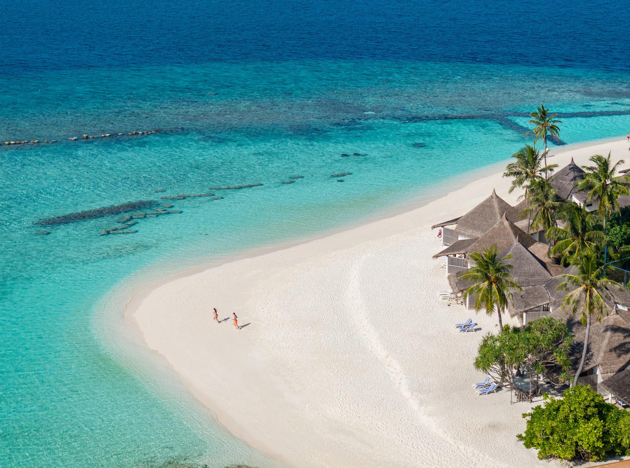 Spiaggia sabbiosa con palme e bungalows davanti al Angaga Island Resort & Spa.
