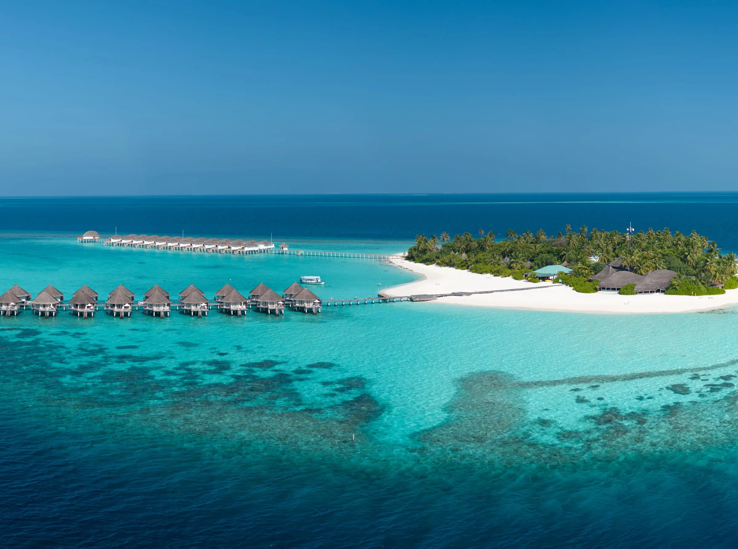 Spiaggia con sabbia bianca e bungalow sull'acqua al Angaga Island Resort & Spa.