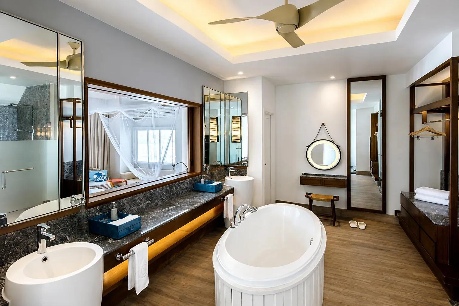 Bagno della Club Sunset Overwater Villa with Pool con vasca da bagno e ampio specchio al Centara Machchafushi Island Resort & Spa Maldives.
