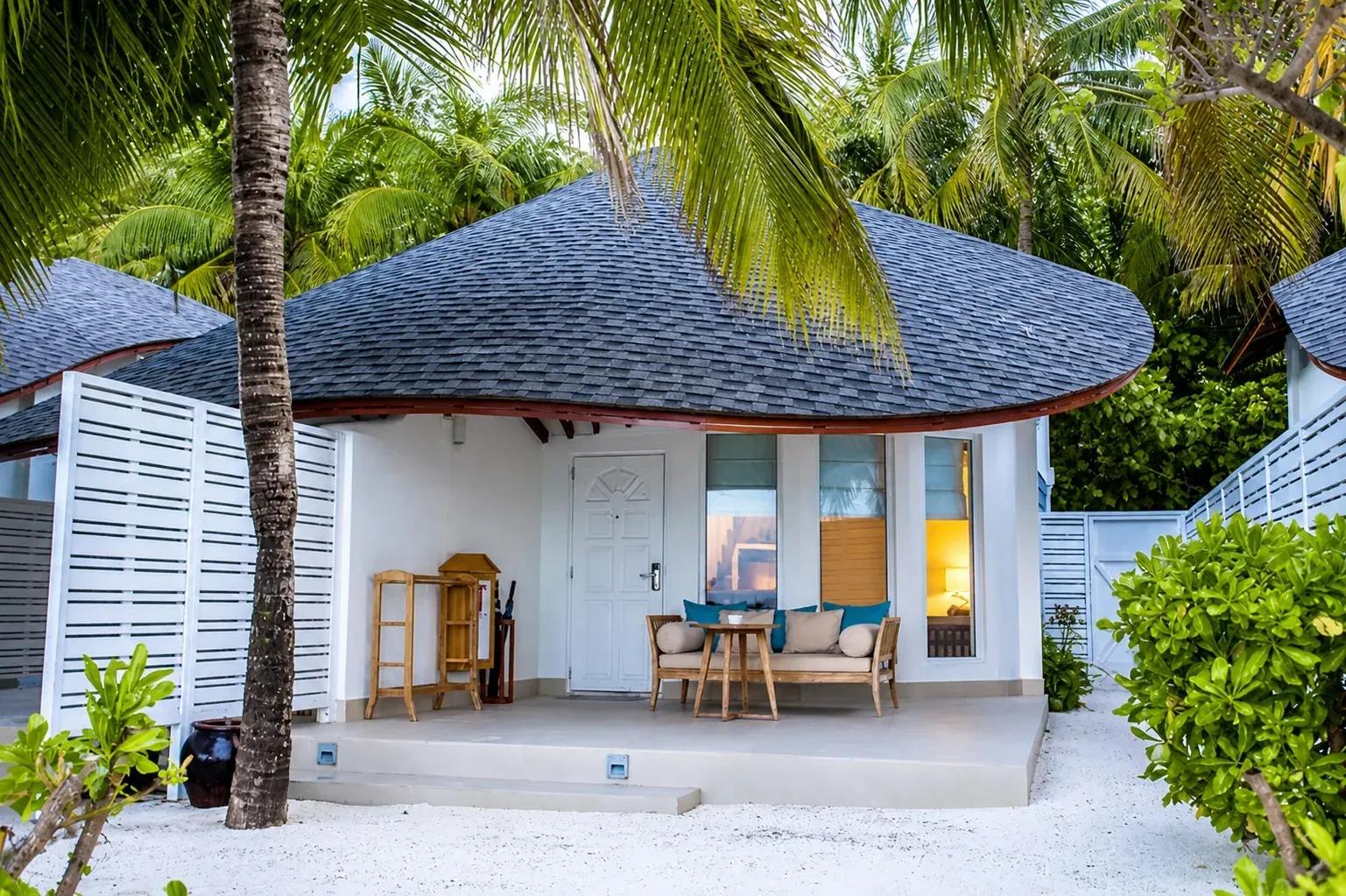 Terrazza della Duplex Beach Villa con divano e vegetazione tropicale al Centara Machchafushi Island Resort & Spa Maldives.
