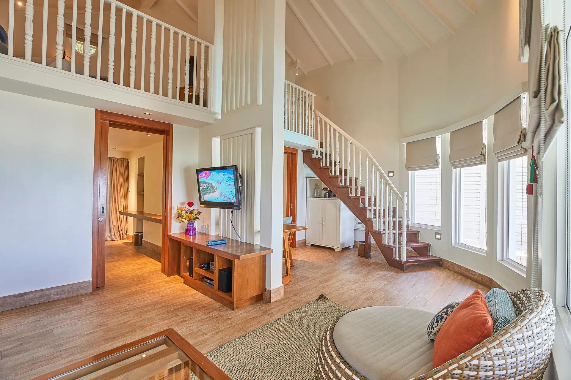 Interno della Duplex Beach Villa con salotto e scala al Centara Machchafushi Island Resort & Spa Maldives.