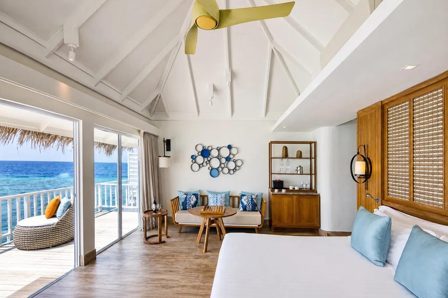 Interno della Family Overwater Villa with Kids Bedroom con letto king, salotto e vista sull'oceano al Centara Machchafushi Island Resort & Spa Maldives.