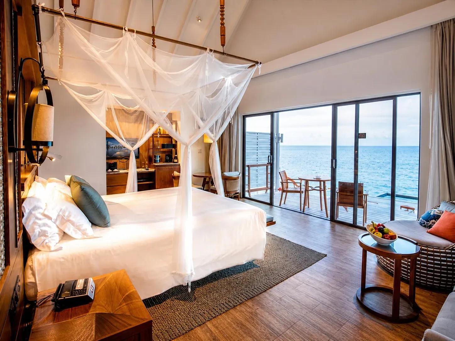 Camera da letto della Reethi Muraka Overwater Villa con vista mare e terrazza al Centara Machchafushi Island Resort & Spa Maldives.