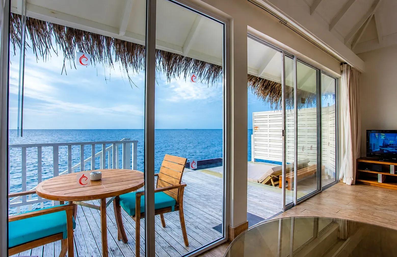 Vista mare dalla terrazza della Sunrise Overwater Villa con sedie in legno al Centara Machchafushi Island Resort & Spa Maldives.