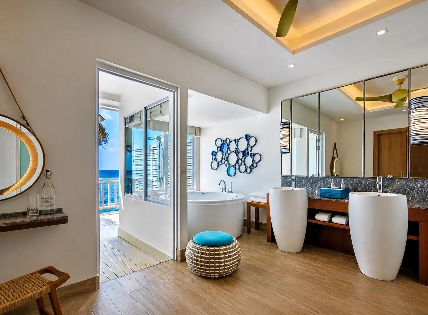 Bagno della Sunrise Overwater Villa con vasca, doppio lavabo e vista mare al Centara Machchafushi Island Resort & Spa Maldives.