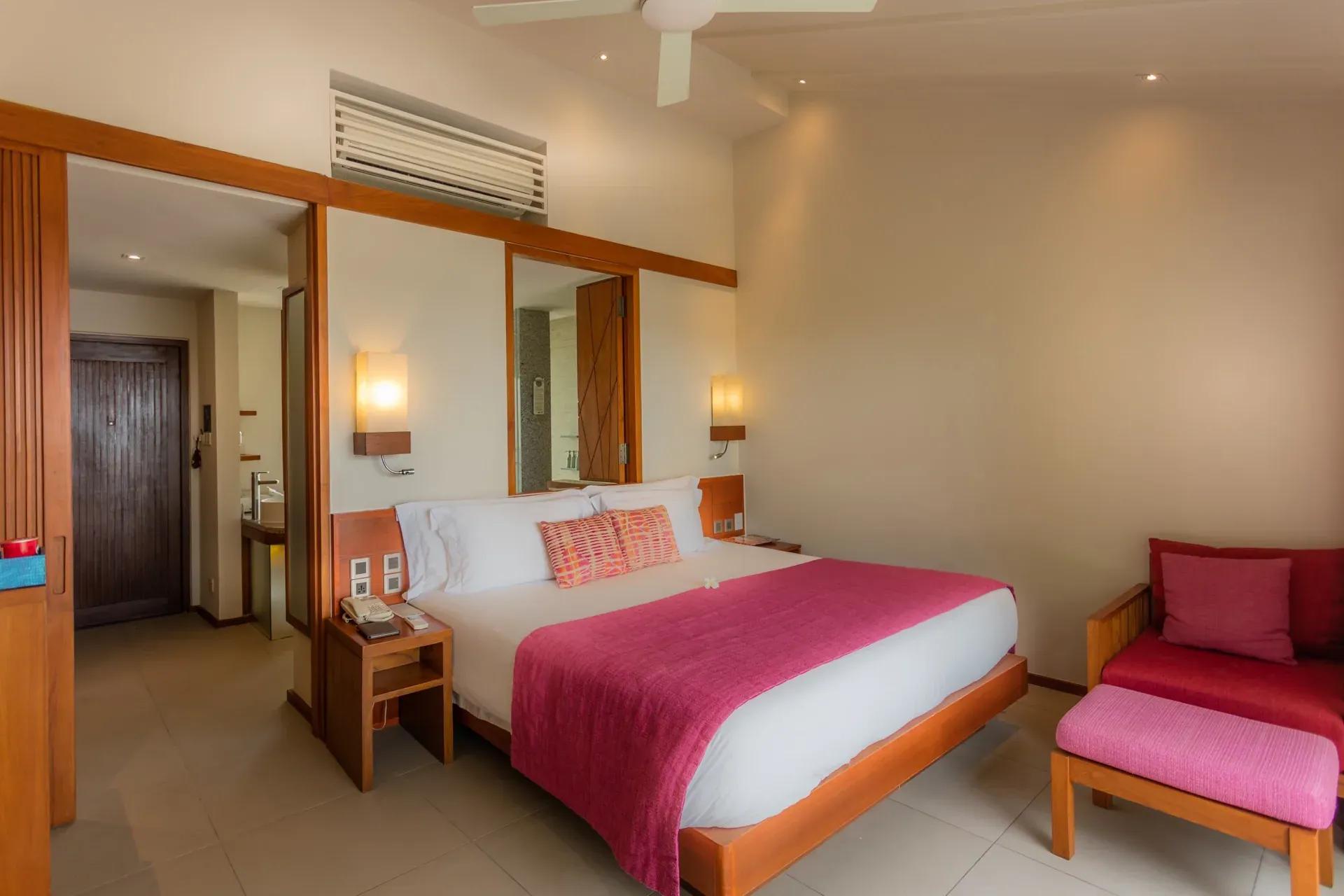 Interno della Lagoon View Beach Villa con letto matrimoniale e divano al Centara Ras Fushi Resort & Spa Maldives.