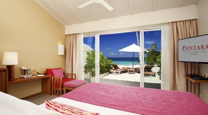 Interno della Lagoon View Beach Villa with Swirl Pool con letto, terrazza e vista sulla spiaggia del Centara Ras Fushi Resort & Spa Maldives.