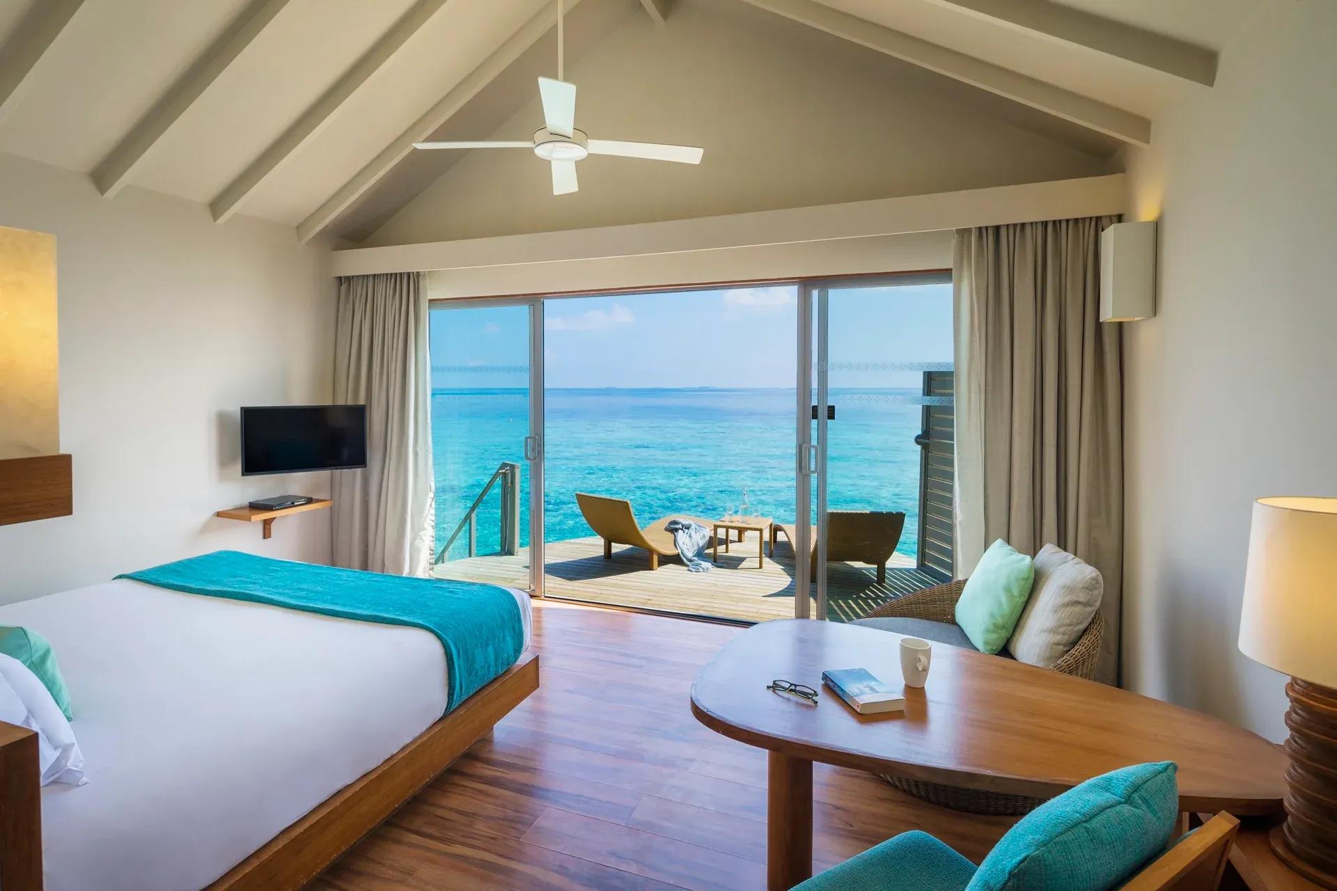 Interno della Overwater Villa con vista mare e terrazza al Centara Ras Fushi Resort & Spa Maldives.