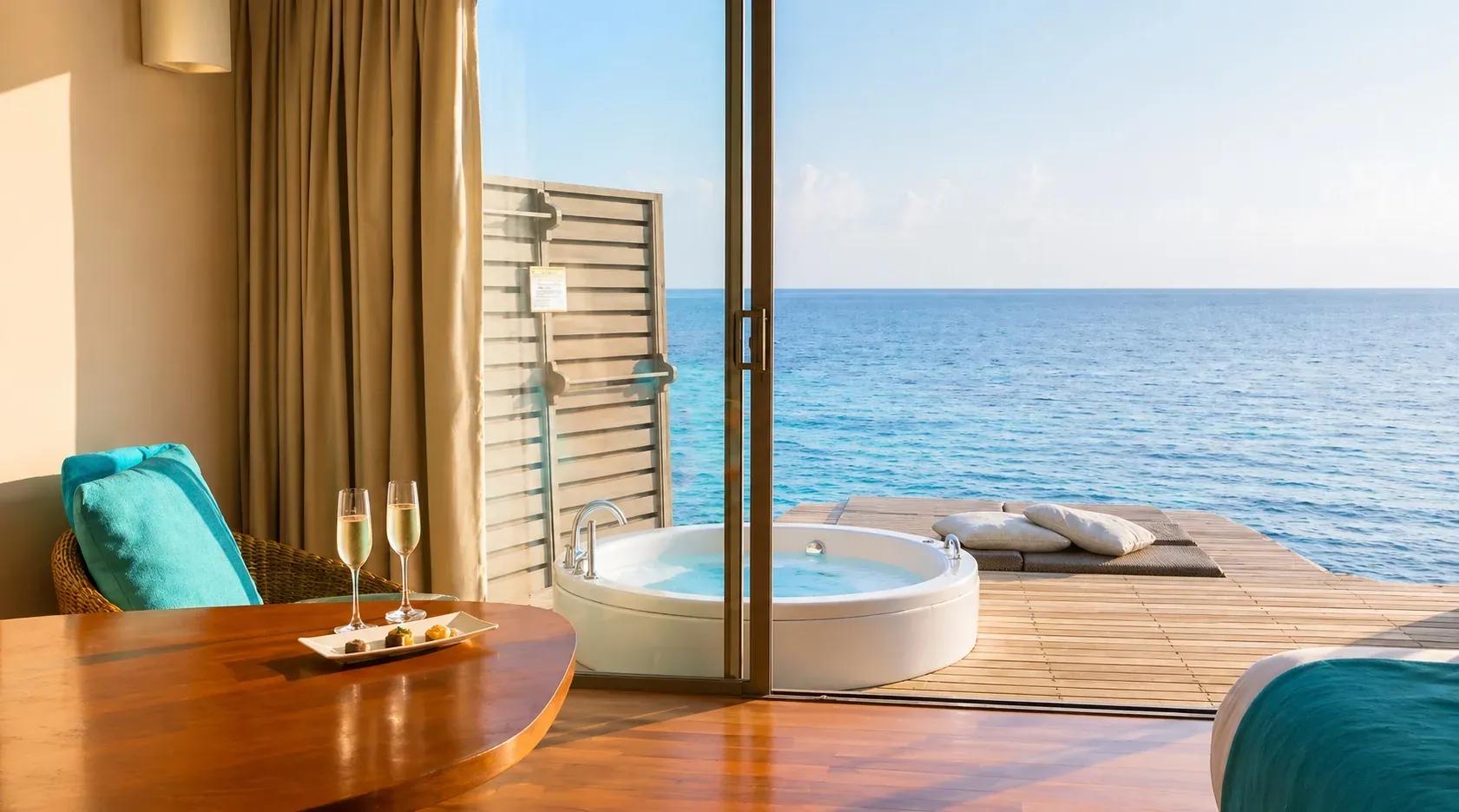 Vista della Sunset Overwater Villa with a Swirl Pool con tavolo in legno e pool vista mare al Centara Ras Fushi Resort & Spa Maldives.