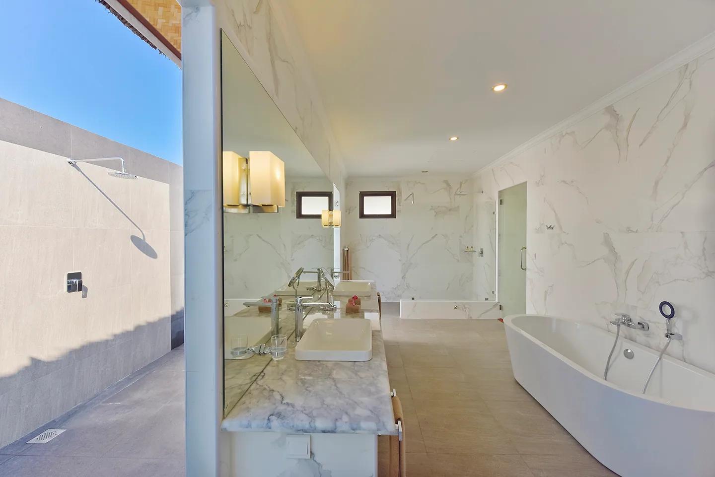 Bagno del Beach Bungalow al Dreamland The Unique Sea And Lake Resort Spa, con pareti in marmo, doppio lavabo, vasca freestanding e una doccia esterna a cielo aperto.