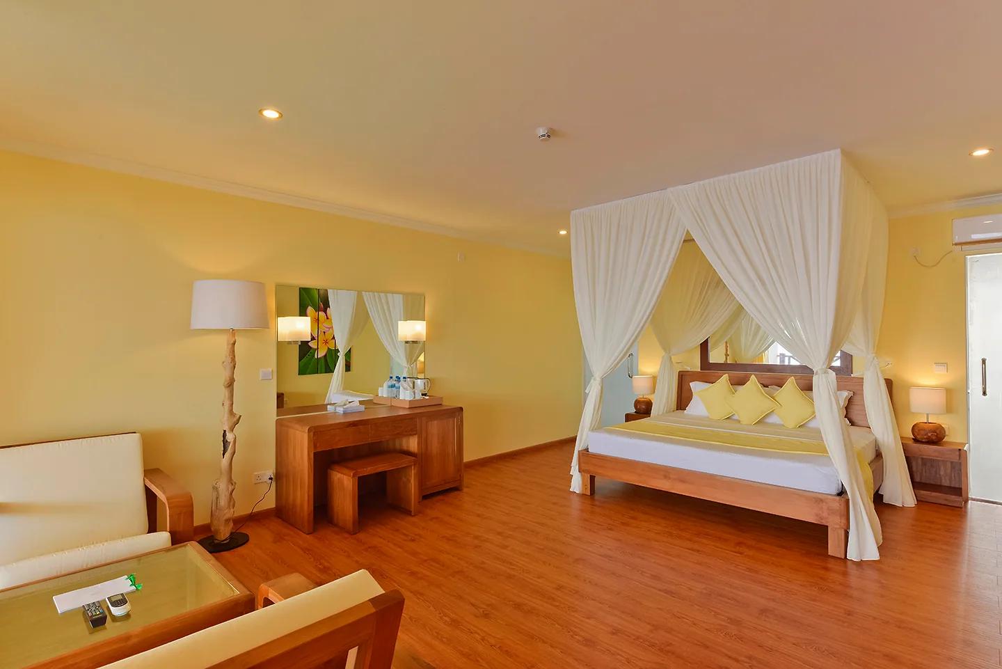 Camera da letto del Water Bungalow al Dreamland The Unique Sea And Lake Resort Spa con letto a baldacchino, arredi in legno, pavimento chiaro e una piccola zona giorno.