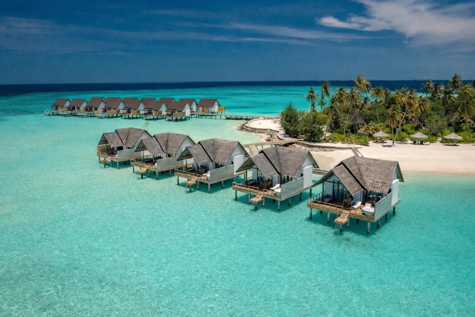 Ville sull'acqua e laguna turchese al Fushifaru Maldives con spiaggia e palme.
