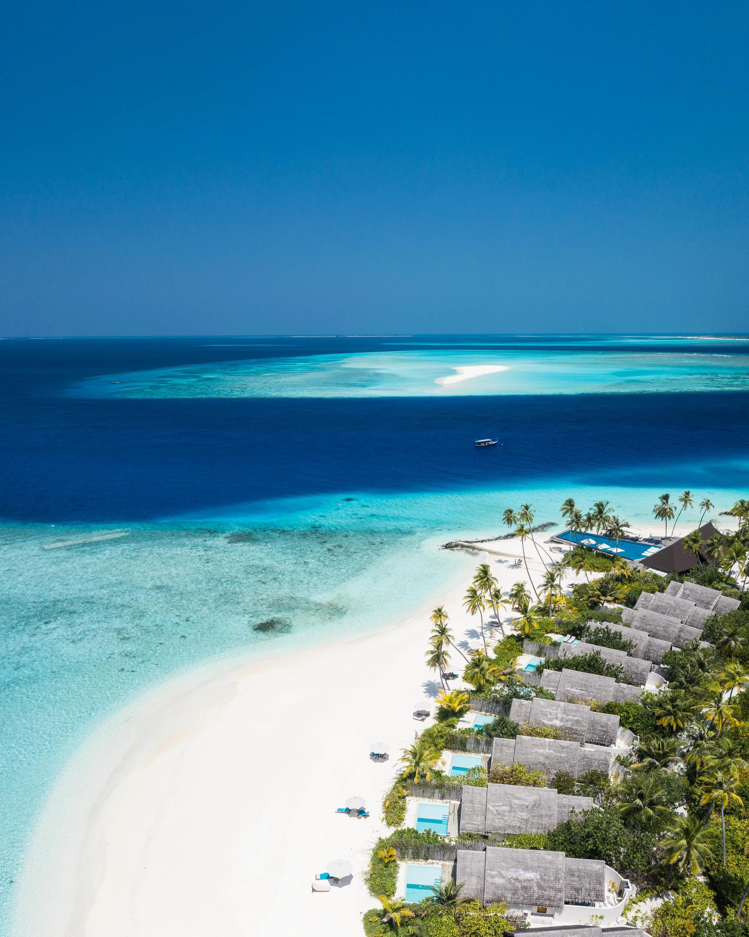 Vista aerea delle ville con piscina privata e spiaggia di sabbia bianca al Fushifaru Maldives.