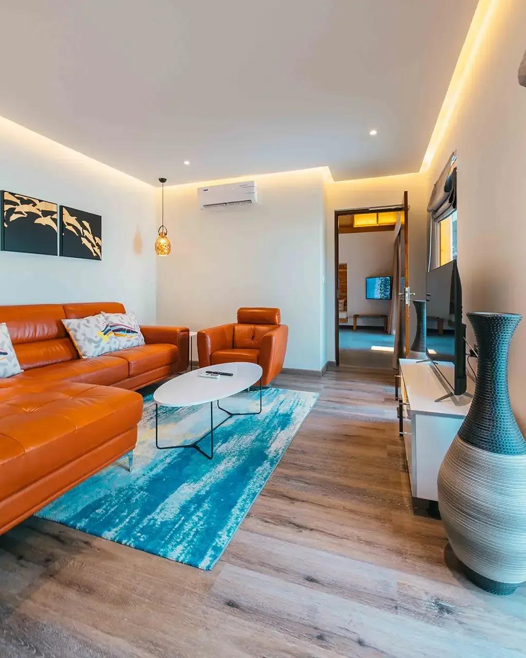Soggiorno della Beach Duplex Villa con divano in pelle e tavolo da caffè al Fushifaru Maldives.