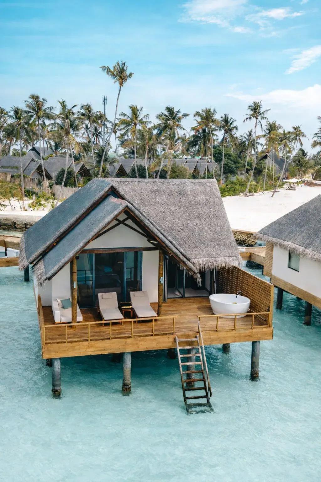 Jacuzzi water villa con vasca rotonda e terrazza in legno sulla laguna turchese del Fushifaru Maldives, circondata da palme