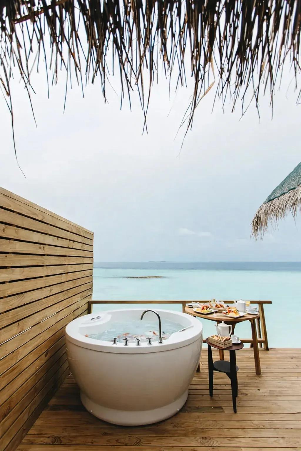 Terrazza della Jacuzzi Water Villa con vasca idromassaggio e vista sull'oceano al Fushifaru Maldives.