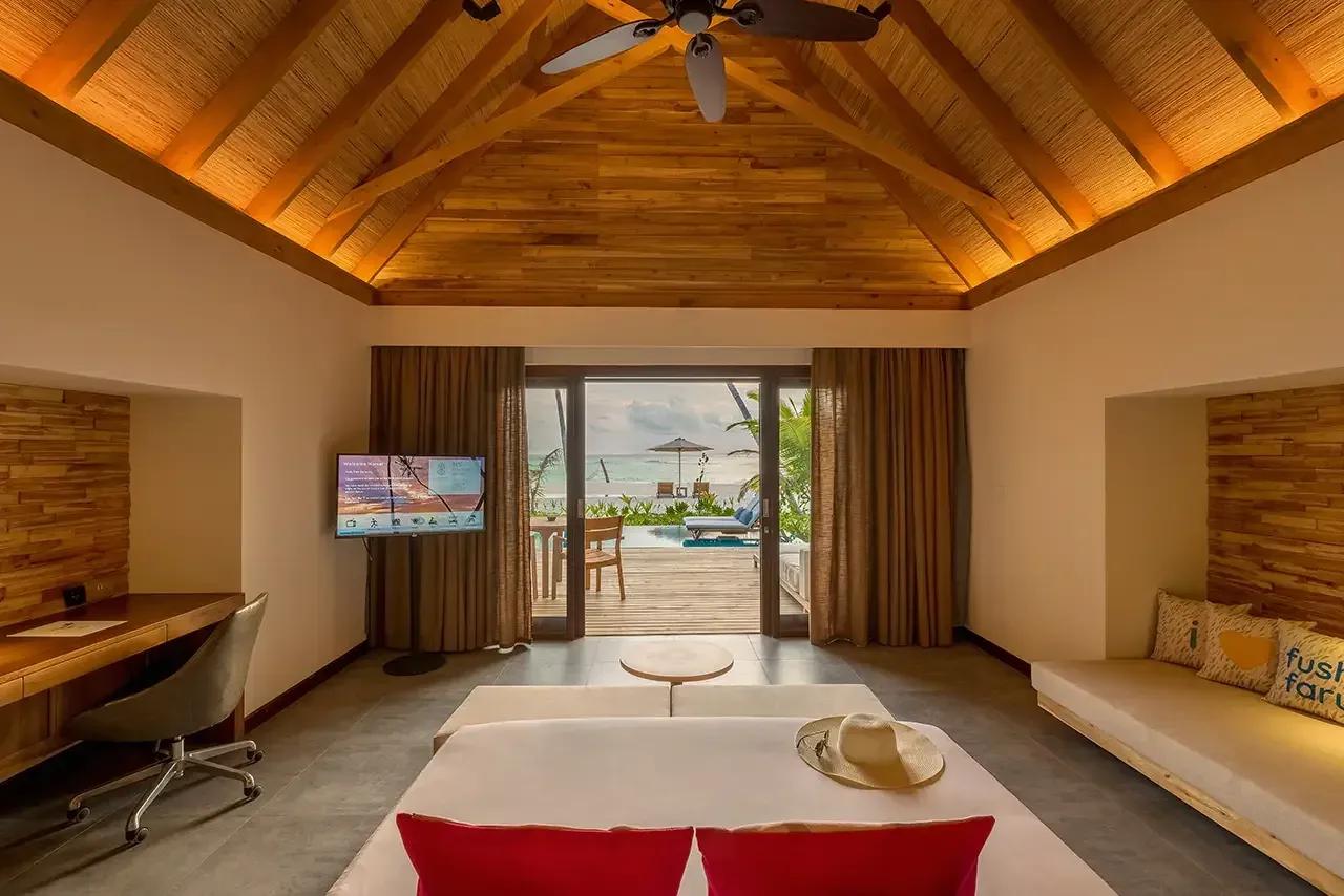 Letto matrimoniale e terrazza con vista piscina nella Pool Beach Villa Sunset del Fushifaru Maldives