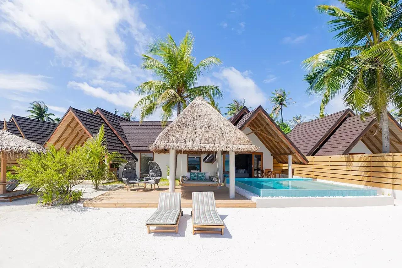 Villa Premium Beach Duplex con piscina privata e lettini sulla spiaggia al Fushifaru Maldives.