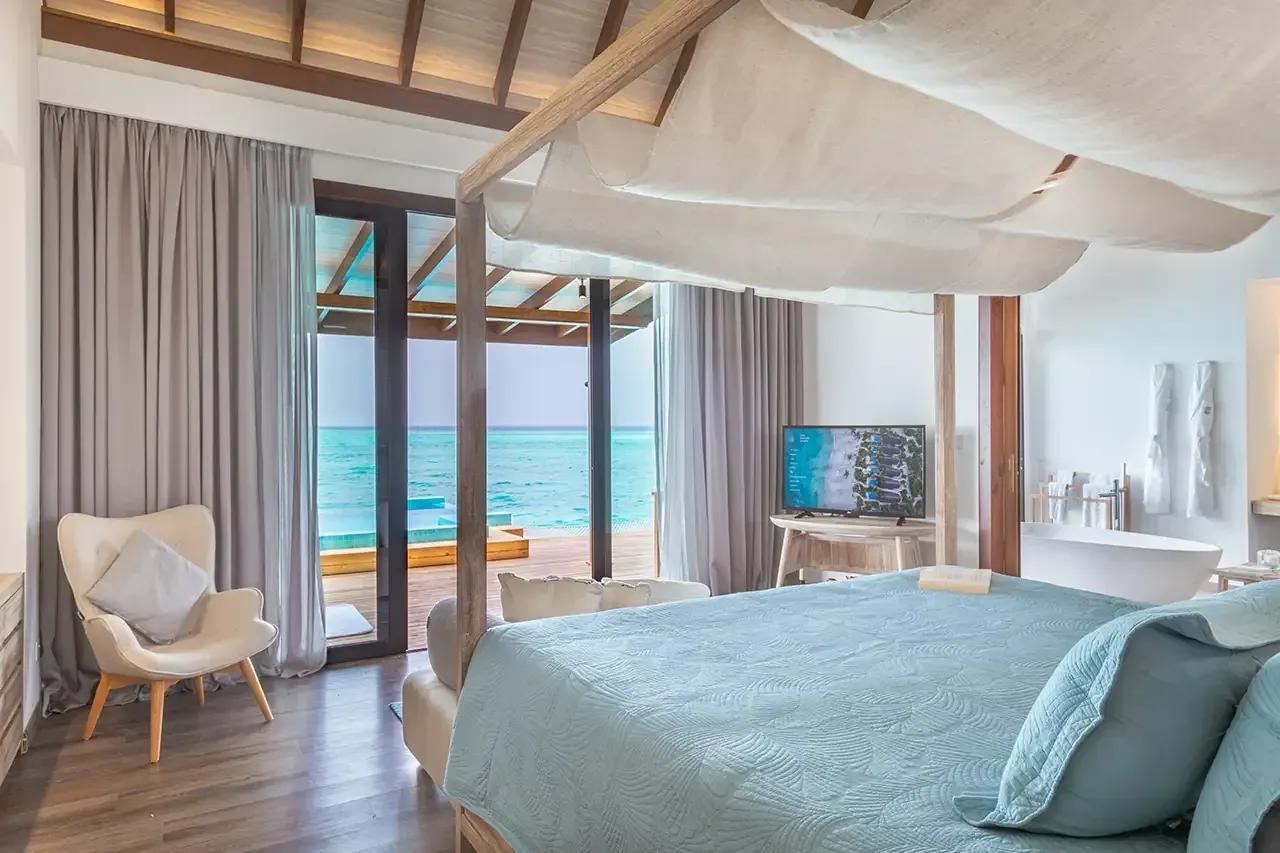 Camera da letto con vista mare e vasca da bagno della premium pool water villa al Fushifaru Maldives