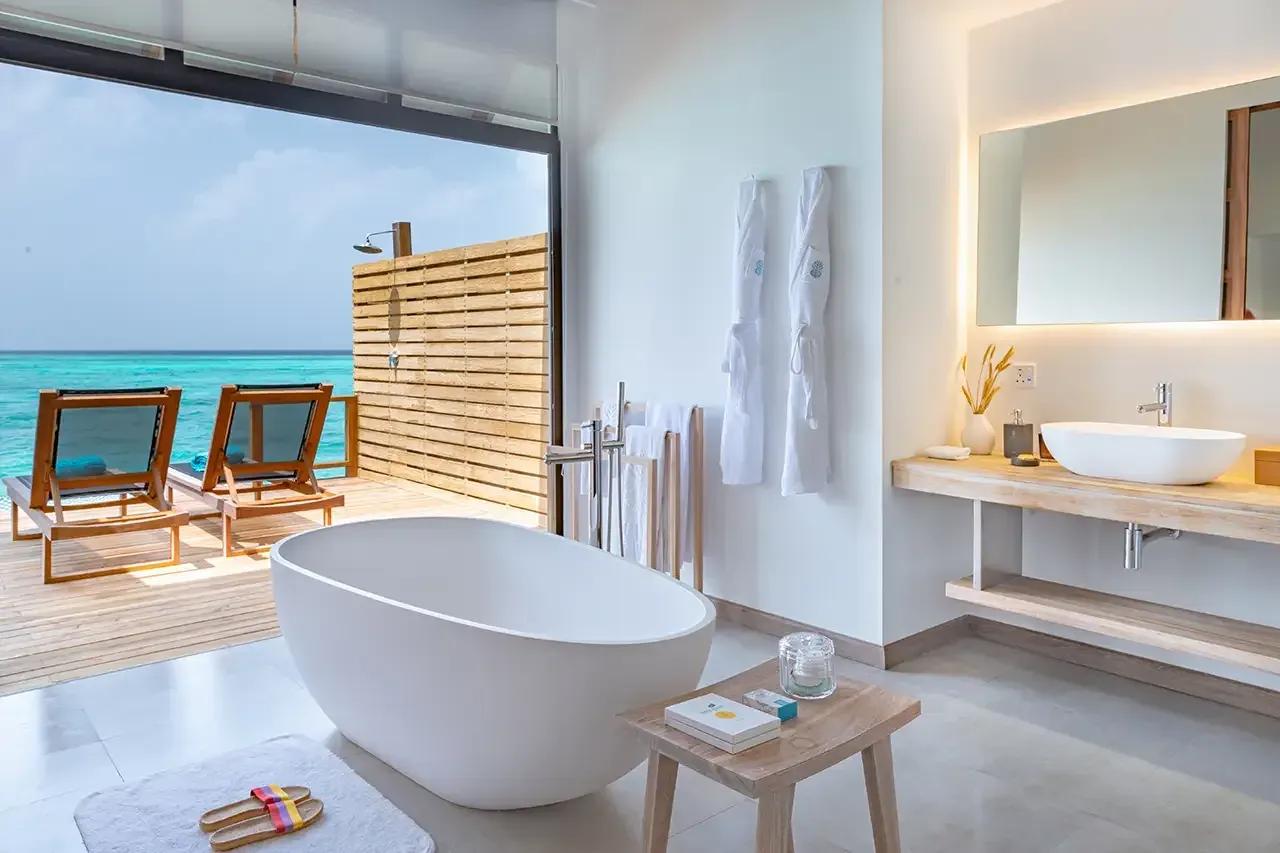 Bagno con vasca e terrazza vista mare nella Premium Pool Water Villa del Fushifaru Maldives.