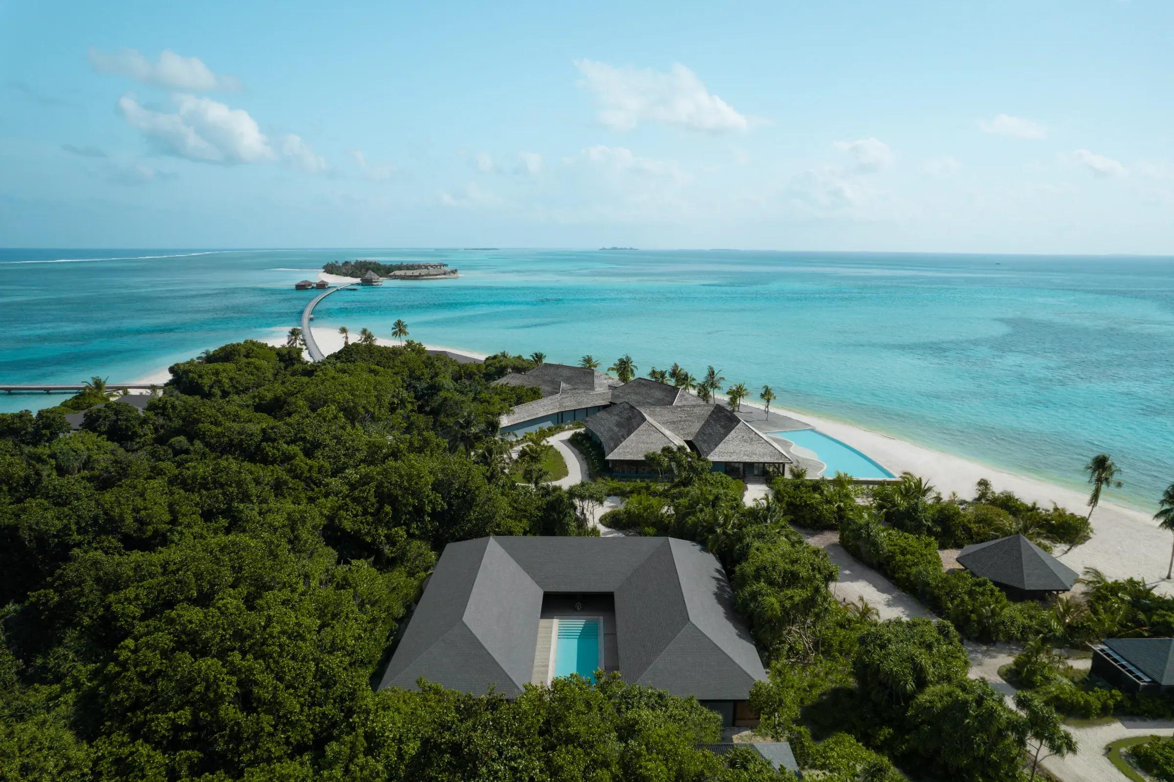 Vista aerea di una piscina e vegetazione al Jawakara Islands Maldives, con mare azzurro sullo sfondo.