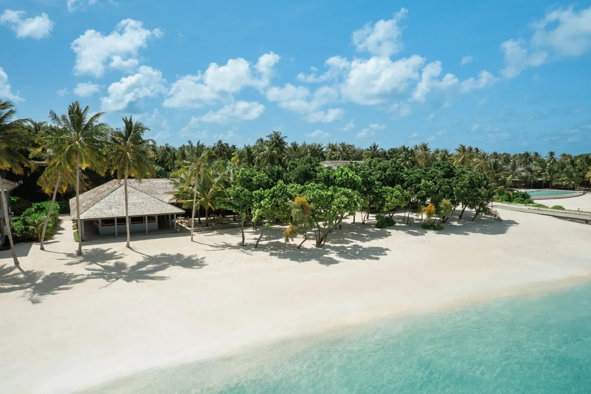Spiaggia con palme e edifici immersi nella vegetazione al Jawakara Islands Maldives.