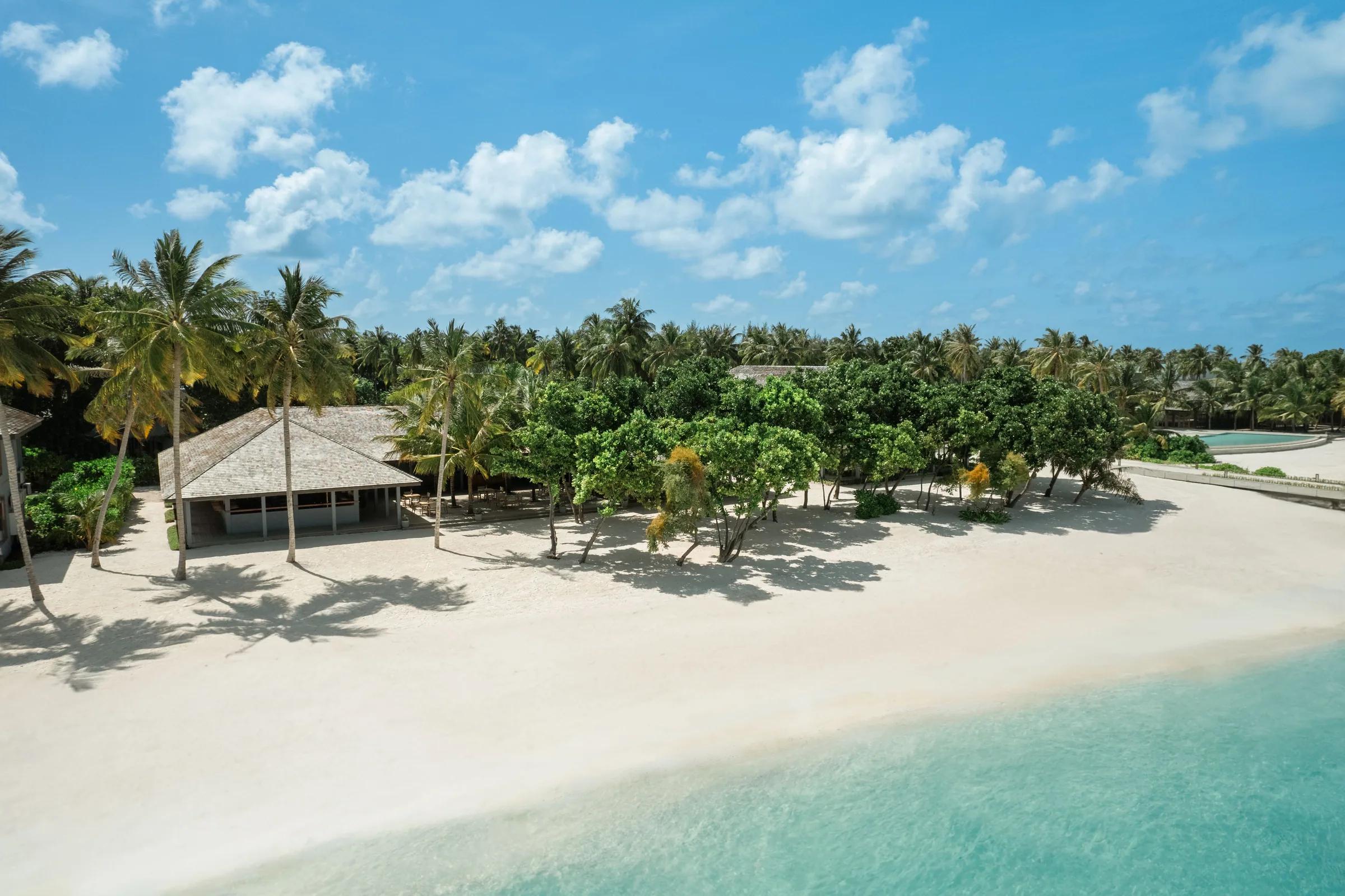 Spiaggia con palme e edifici immersi nella vegetazione al Jawakara Islands Maldives.