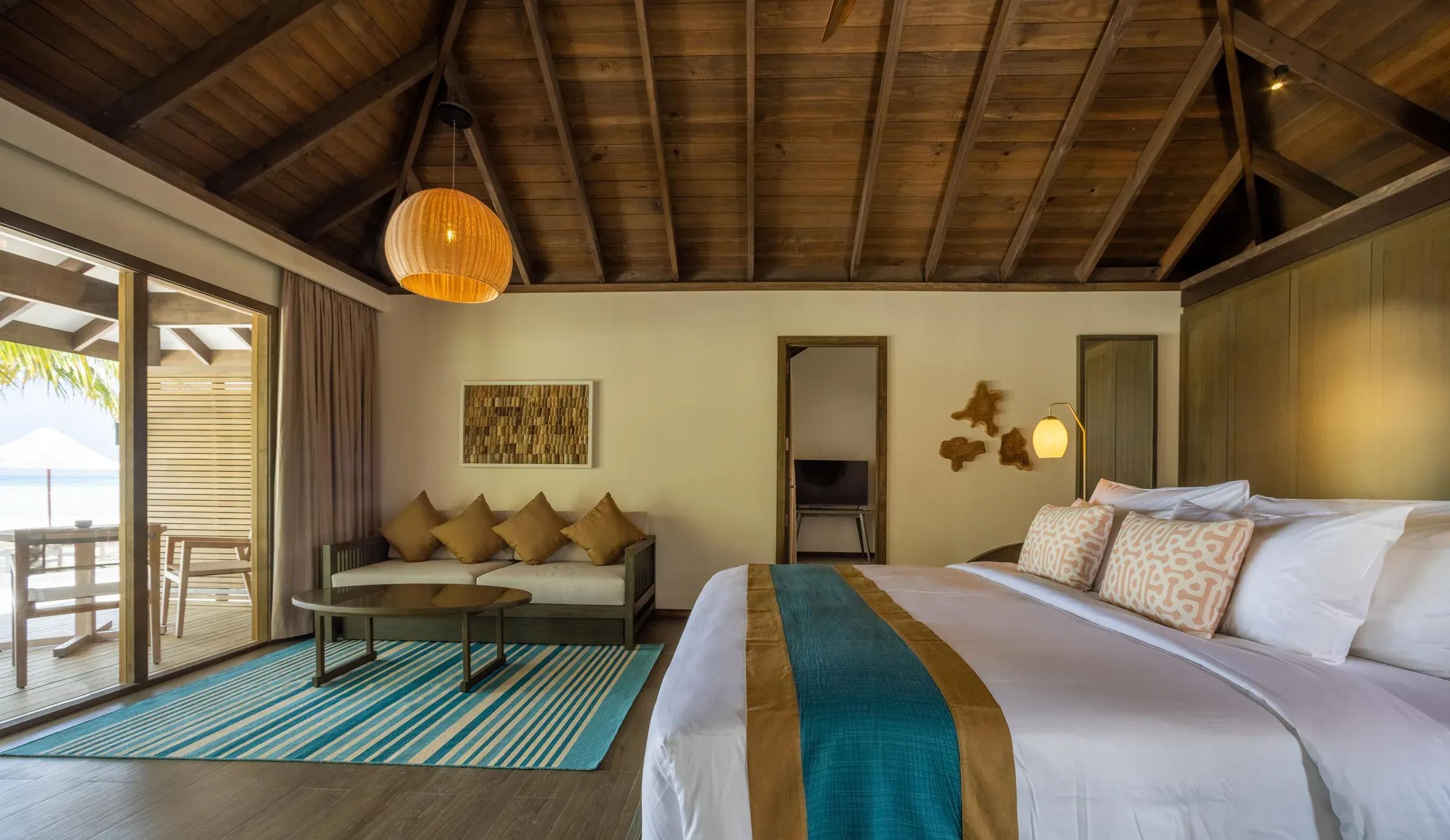 Camera Dheru Three Bedroom Villa con letto, sofà e vista mare al Jawakara Islands Maldives.