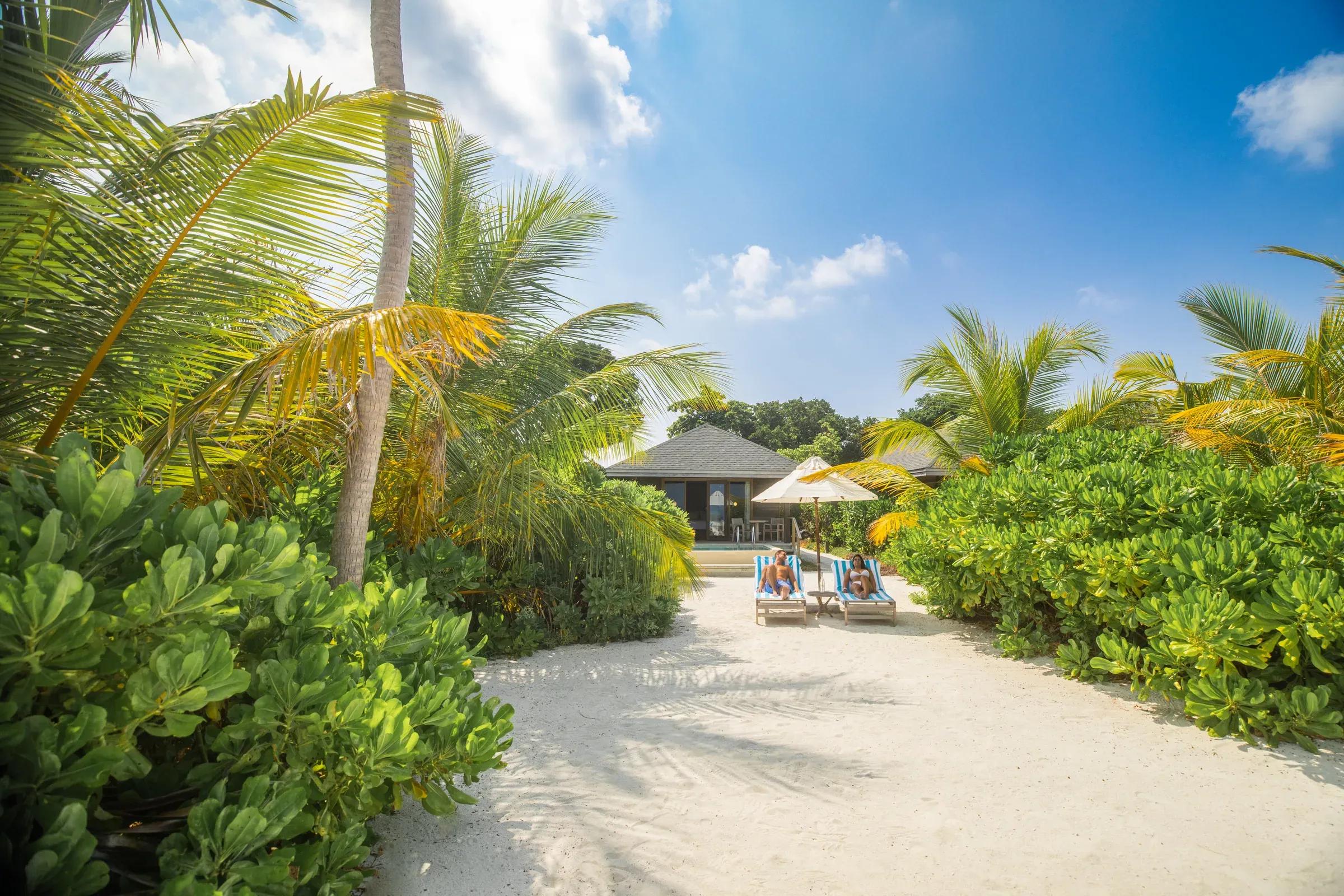 Spiaggia con lettini e ombrellone di fronte alla Mabin Beach Pool Villa del Jawakara Islands Maldives.