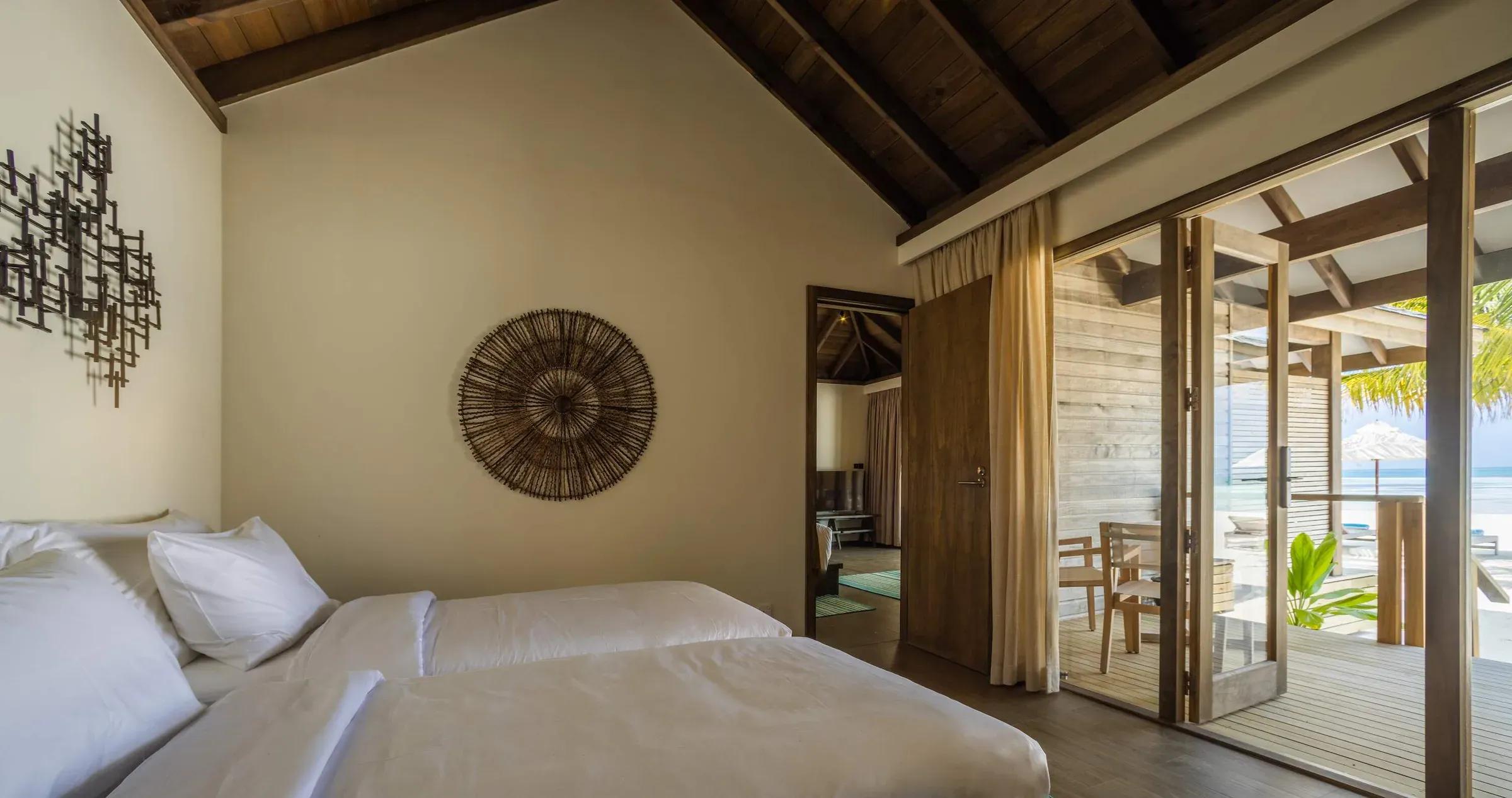 Camera da letto della Mabin Three Bedroom Villa con vista sulla terrazza e spiaggia al Jawakara Islands Maldives.