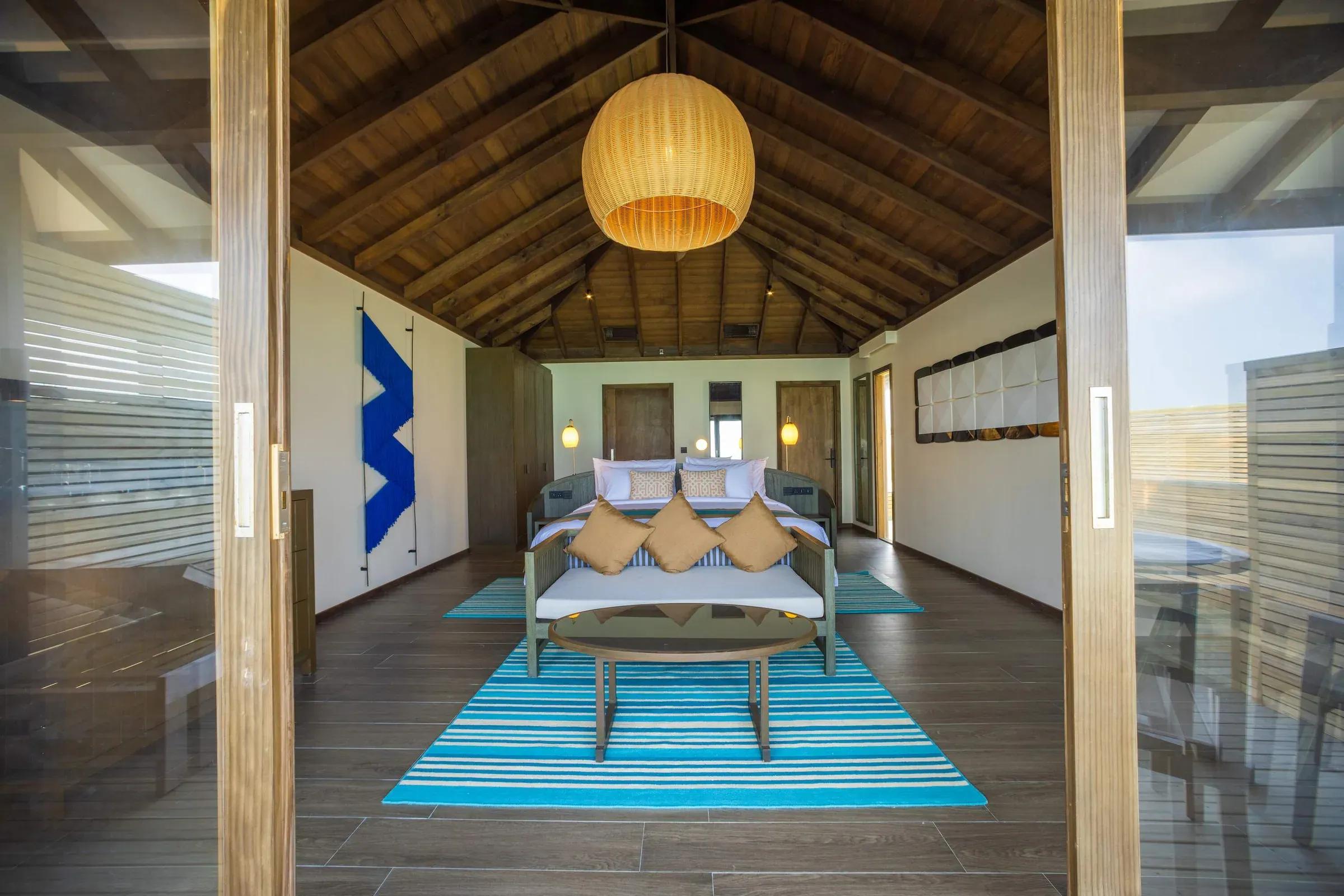 Interno della Mabin Water Pool Villa con soffitto in legno e arredamento moderno al Jawakara Islands Maldives.