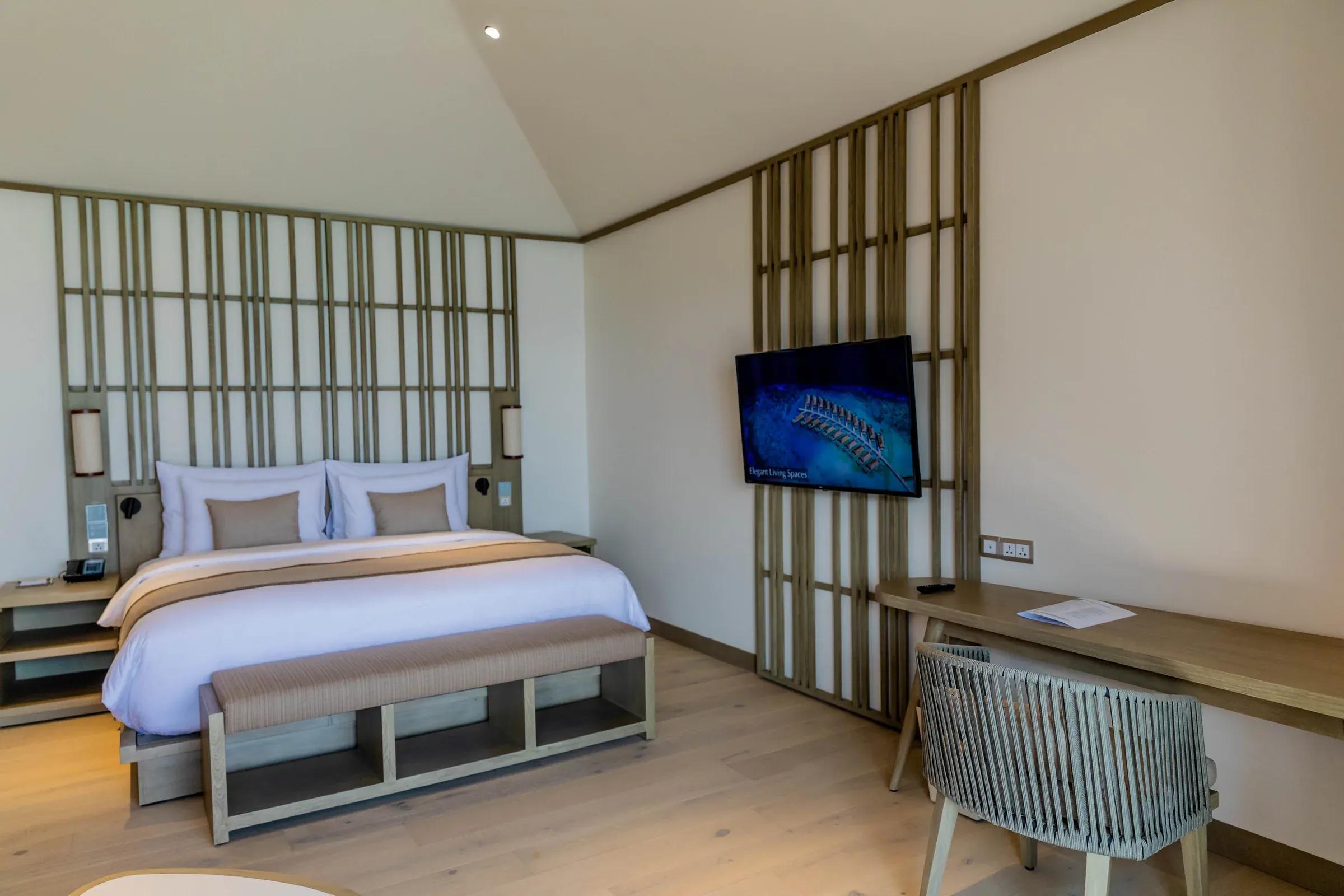 Camera da letto con letto matrimoniale, televisore a parete e scrivania nella Lagoon Pool Villa al Kagi Maldives Spa Island.