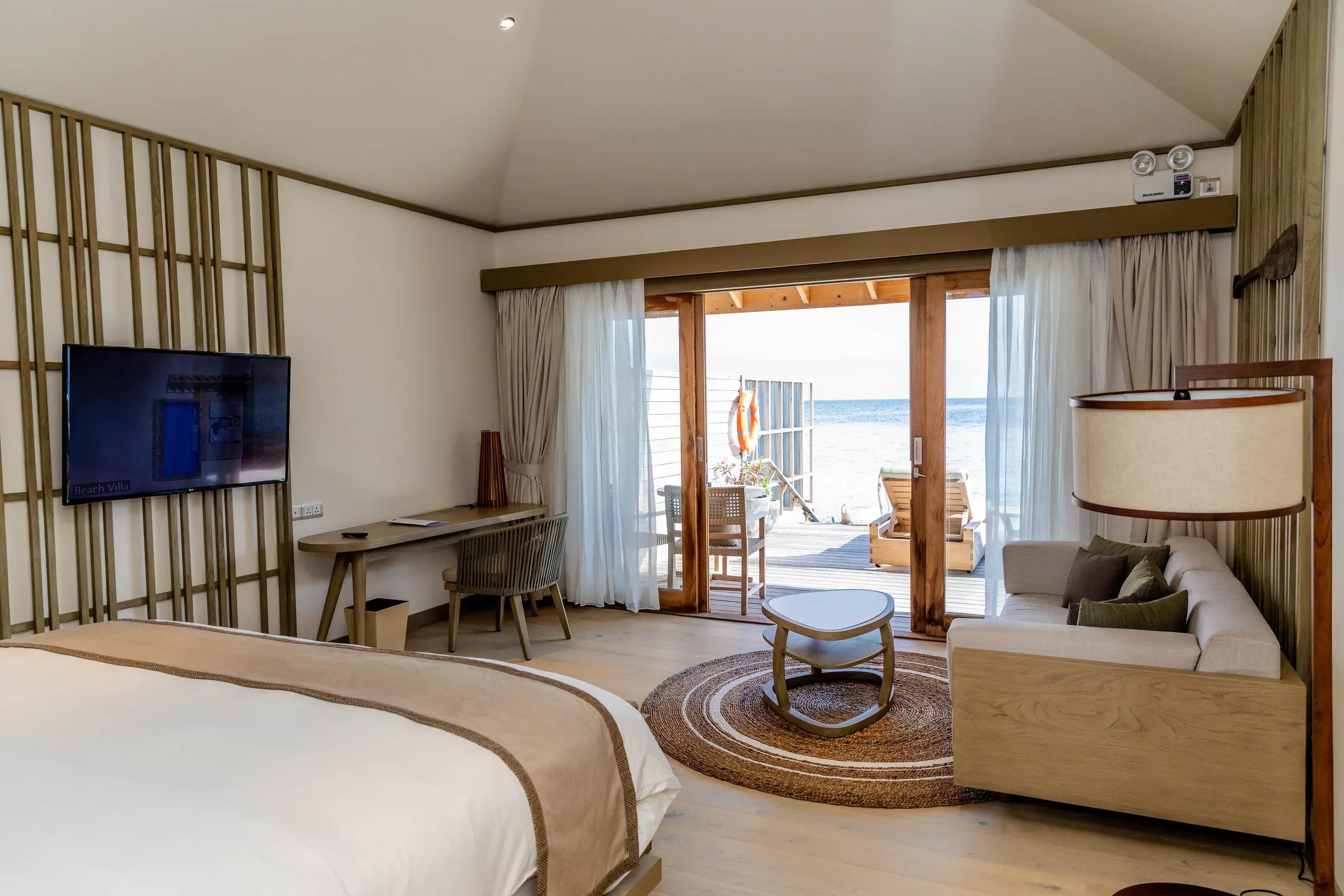 Interno della Lagoon Pool Villa con letto, area salotto e vista sul mare del Kagi Maldives Spa Island.