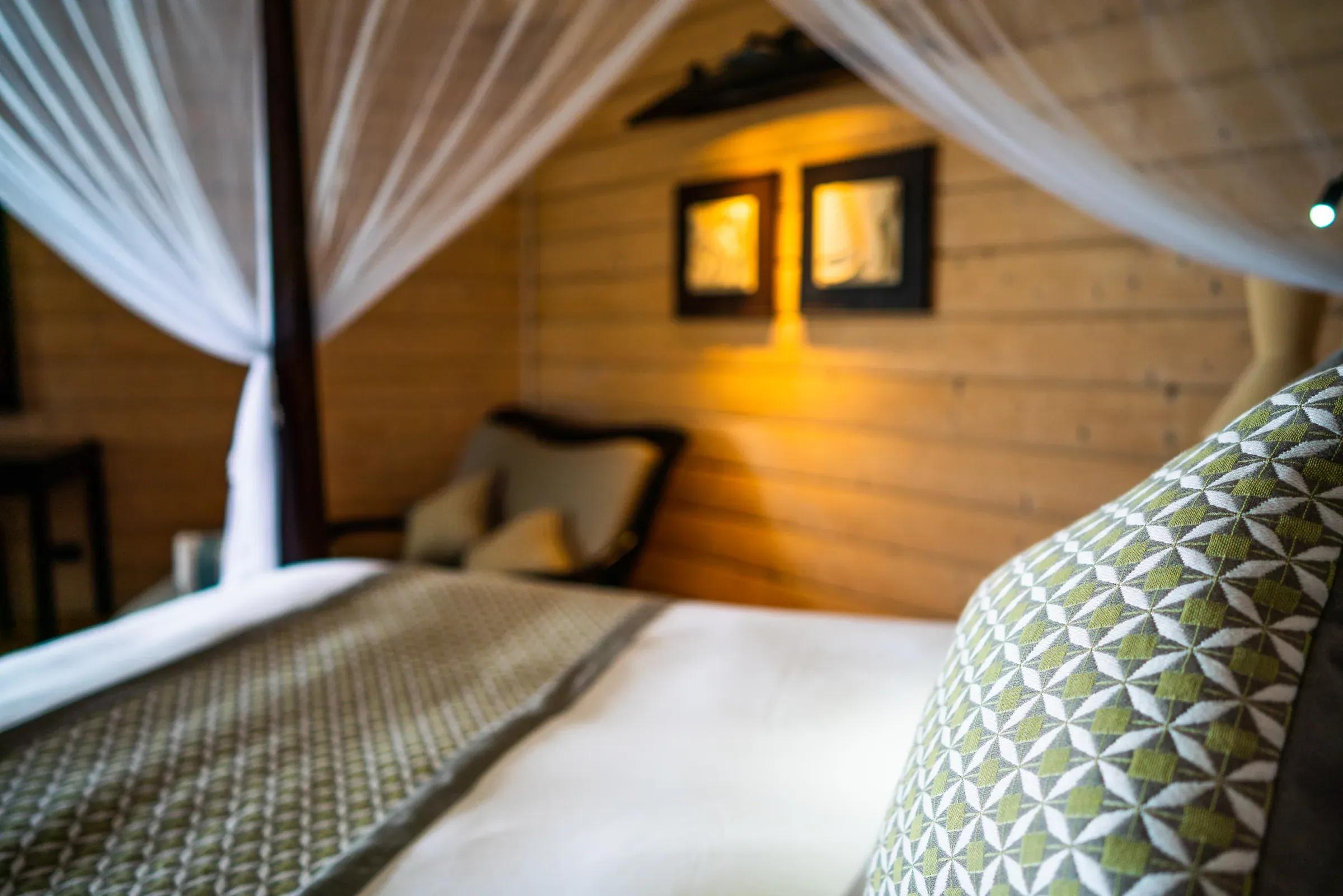 Interno della Beach Villa con letto matrimoniale e poltrona al Komandoo Island Resort & Spa.