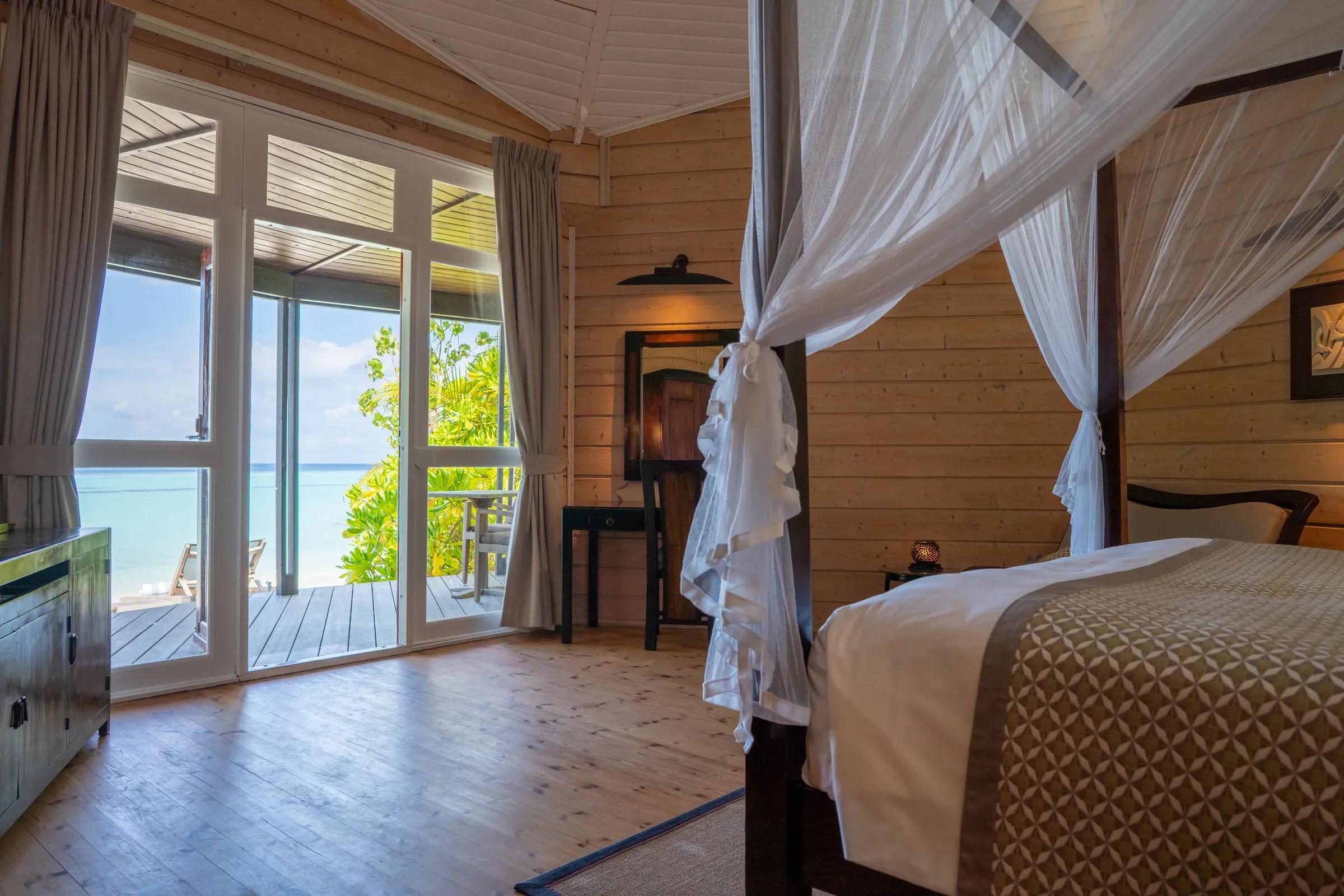 Interni della Beach Villa con letto a baldacchino e vista sul mare del Komandoo Island Resort & Spa.