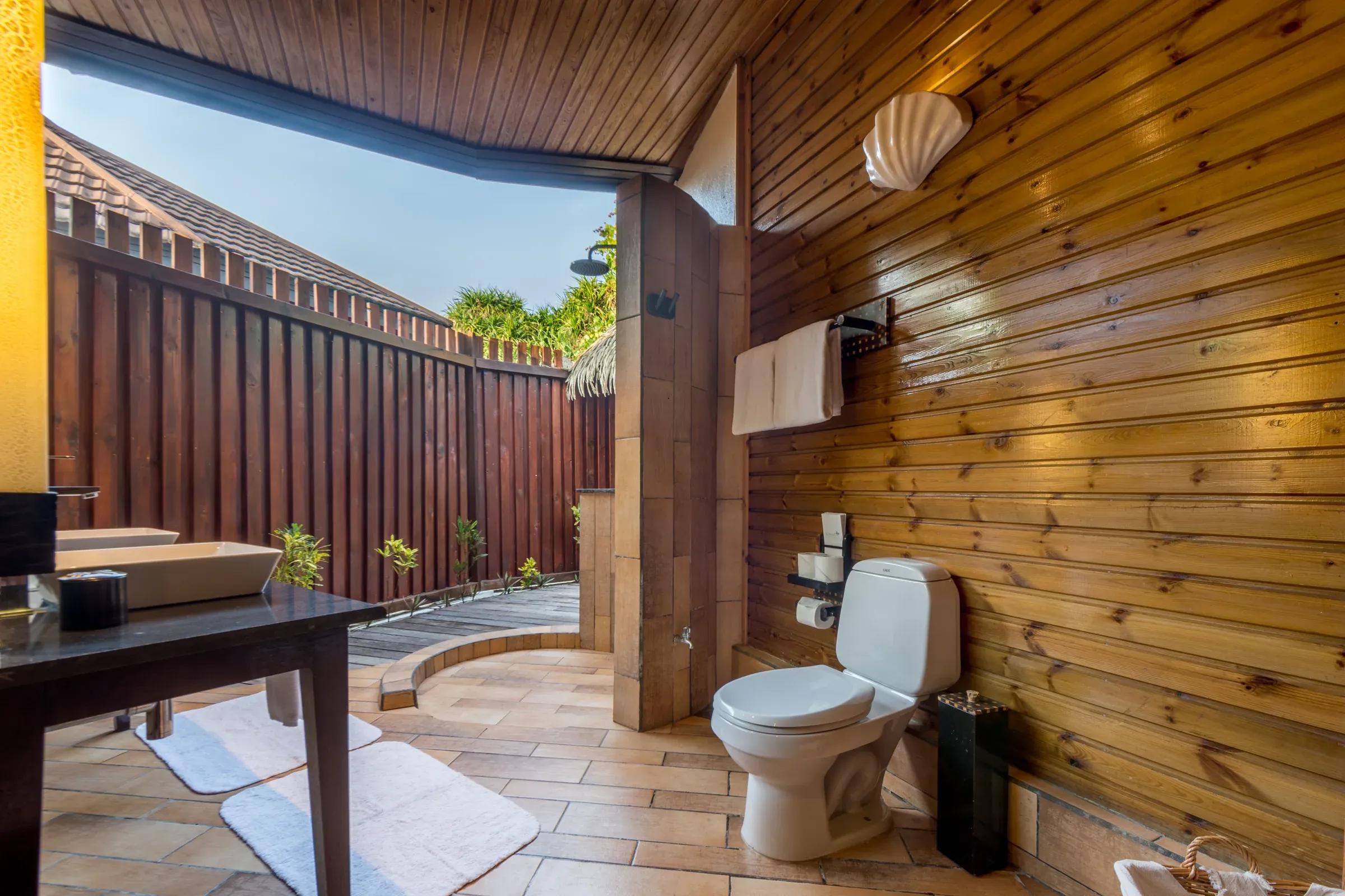 Bagno della Jacuzzi Beach Villa con doccia a cielo aperto e rivestimenti in legno al Komandoo Island Resort & Spa.