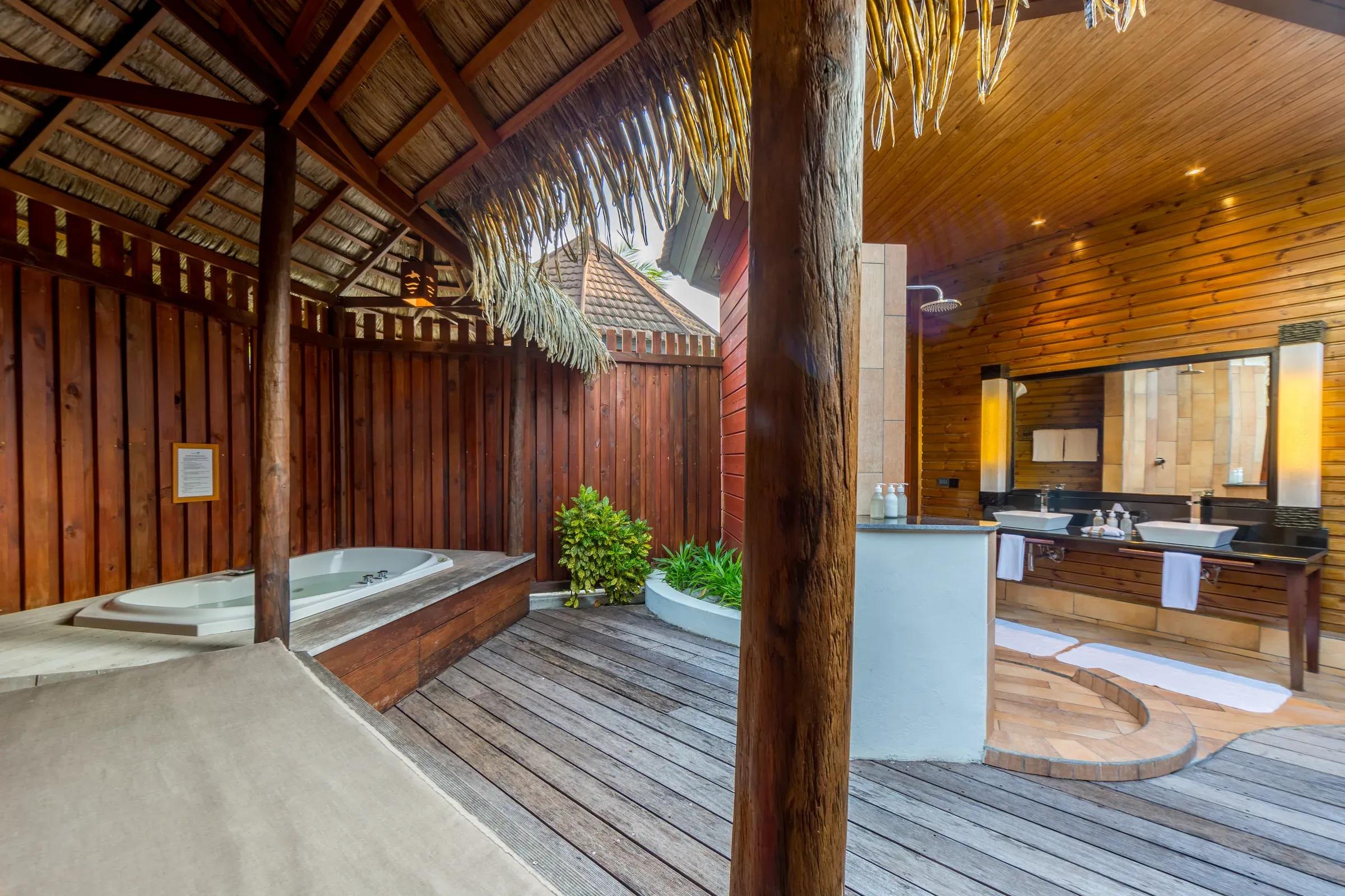 Vista del bagno della Jacuzzi Beach Villa con jacuzzi, doppio lavabo e doccia esterna al Komandoo Island Resort & Spa.
