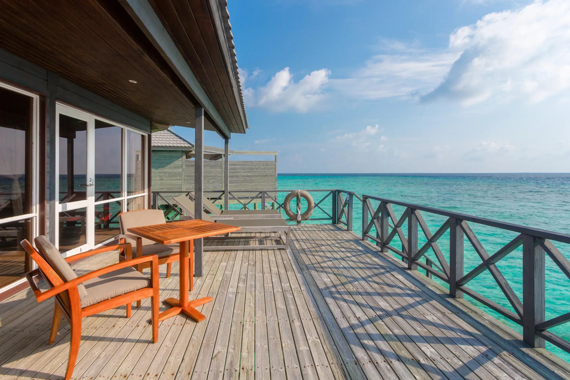 Terrazza della Jacuzzi Water Villa con sedie in legno e vista sull'oceano al Komandoo Island Resort & Spa.