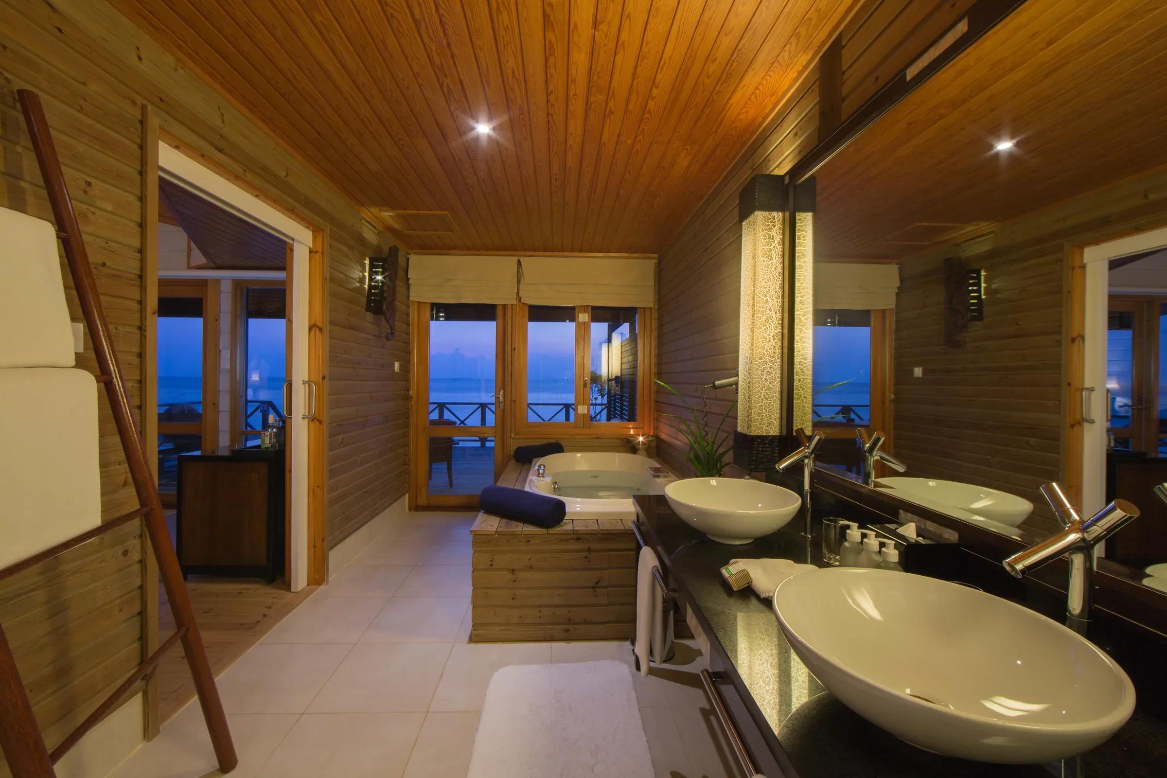 Interno della Jacuzzi Water Villa con vasca, doppio lavabo e vista mare al Komandoo Island Resort & Spa.