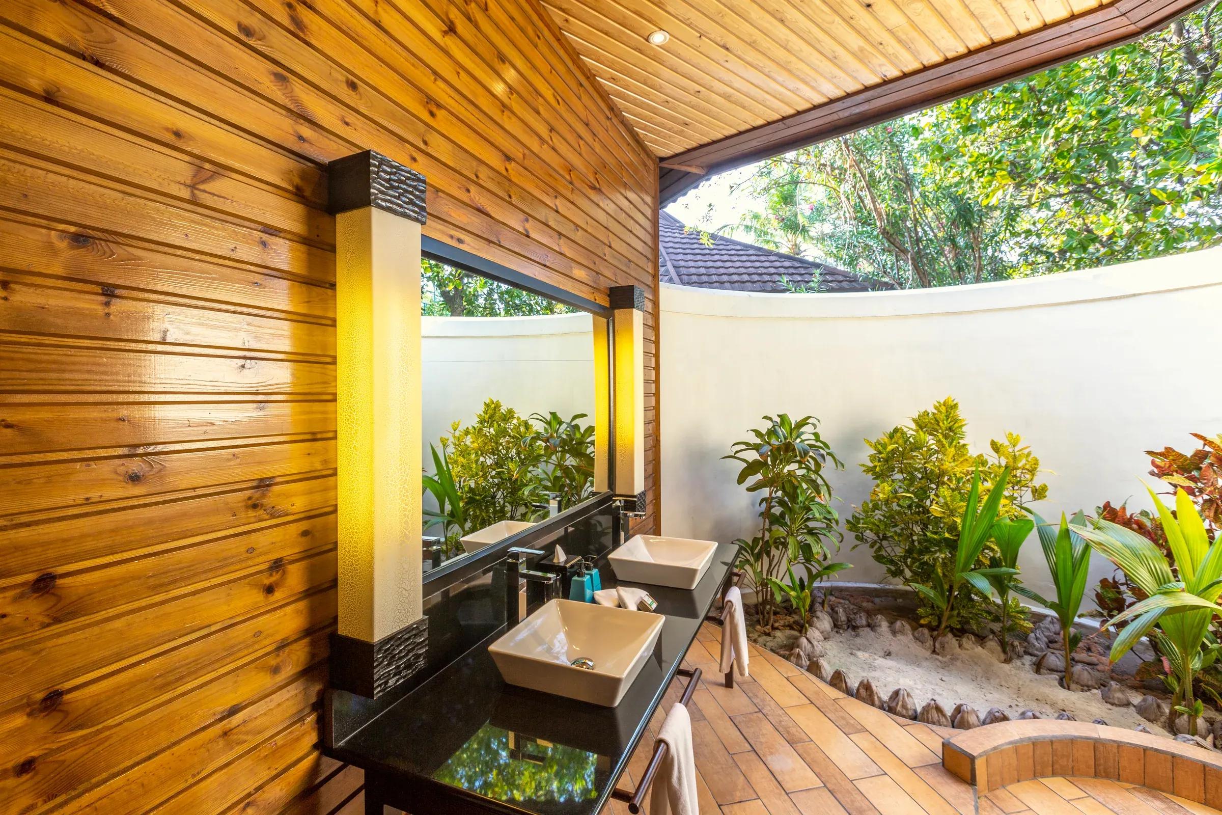 Bagno della Premium Jacuzzi Beach Villa con doppio lavabo e vista sul giardino al Komandoo Island Resort & Spa.