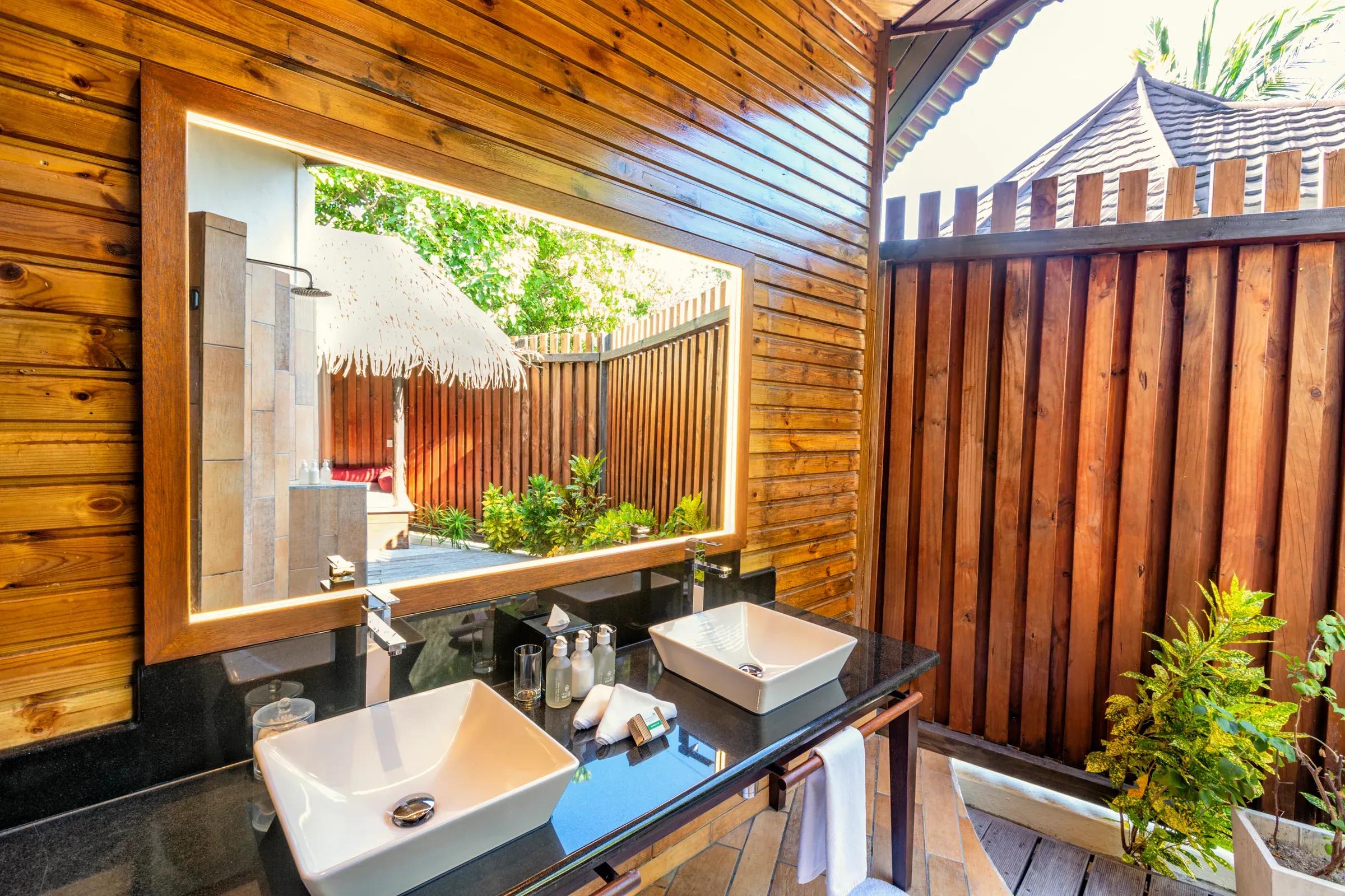 Bagno della Premium Jacuzzi Beach Villa con doppio lavabo e vista sul patio del Komandoo Island Resort & Spa.