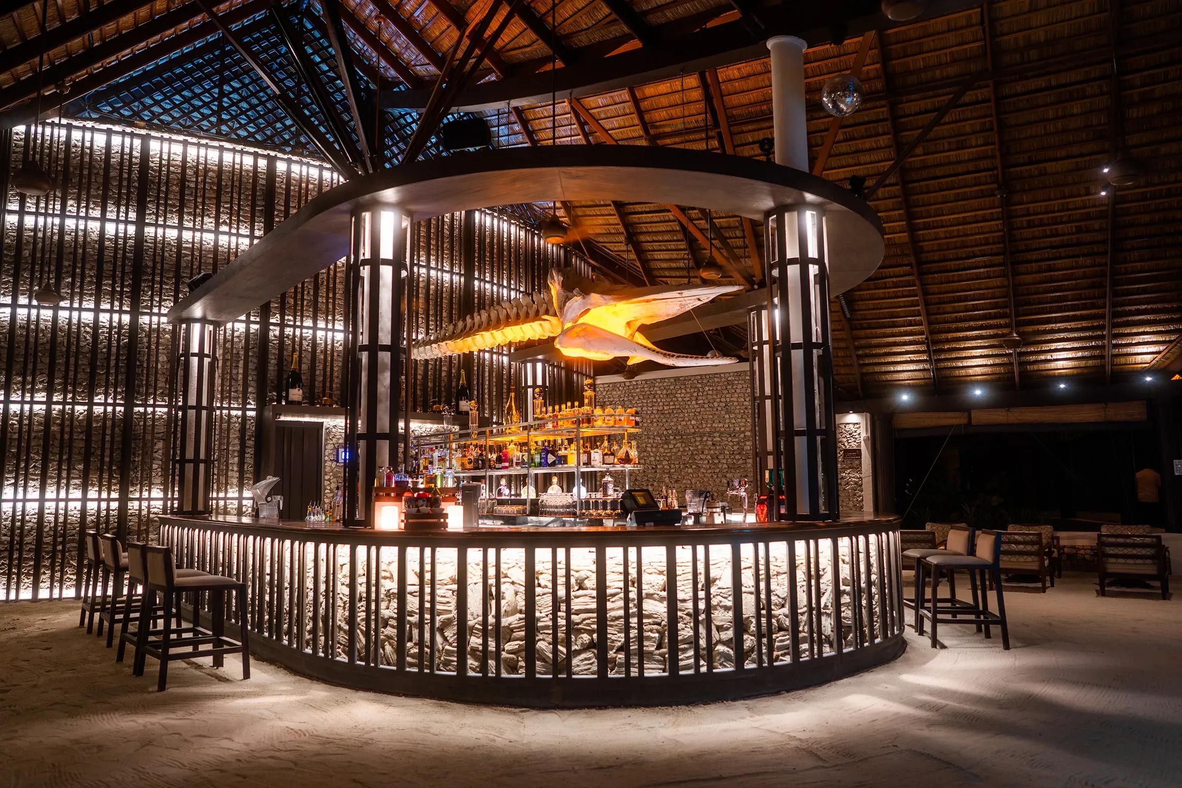 Interno del Babuna Bar con bancone illuminato e sedie al Kuredu Island Resort & Spa