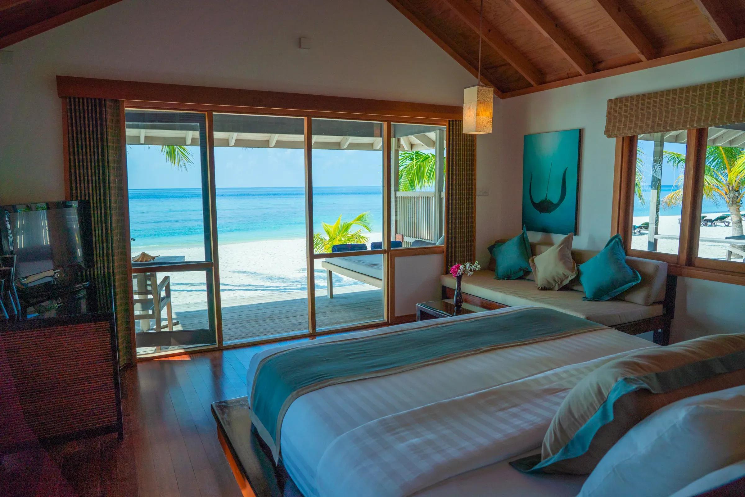 Vista interna della Beach Villa con letto, divano e accesso diretto alla spiaggia del Kuredu Island Resort & Spa.
