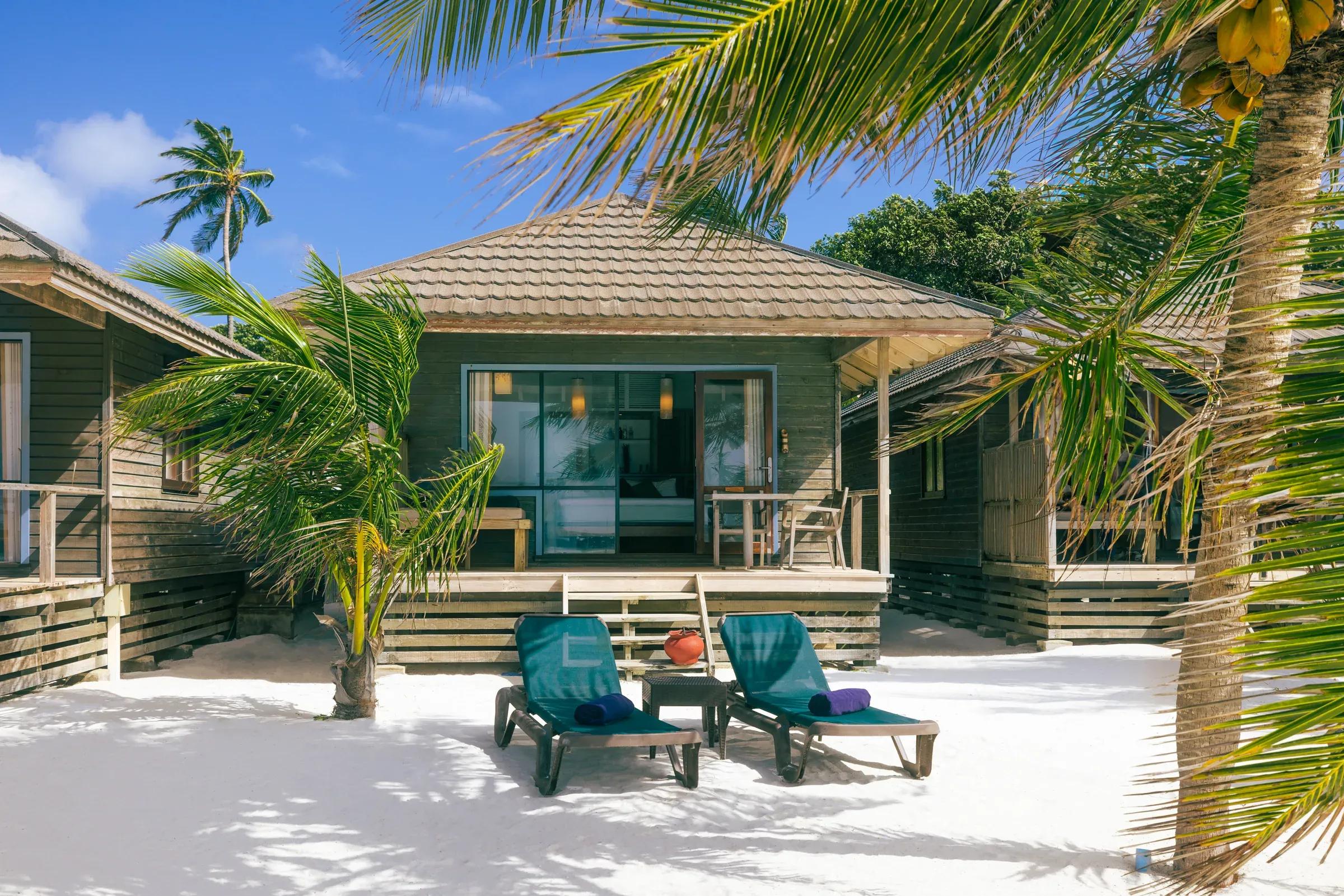 Veranda della Beach Villa con sedie e lettini sulla sabbia al Kuredu Island Resort & Spa