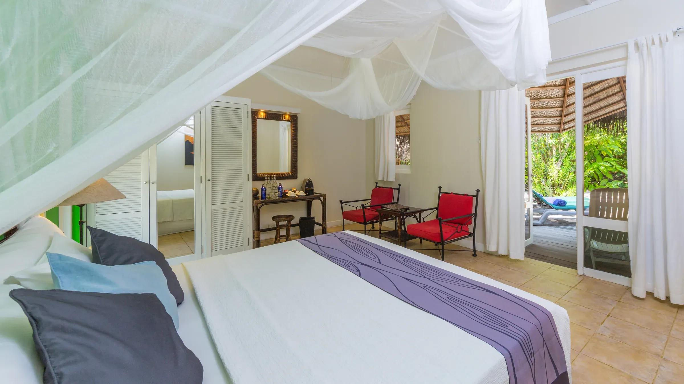 Interno del Garden Bungalow con letto a baldacchino e area salotto al Kuredu Island Resort & Spa.