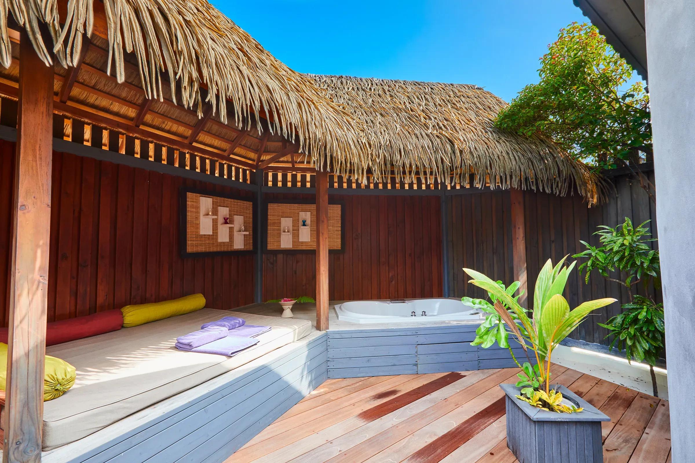 Area esterna della Jacuzzi Beach Villa con vasca idromassaggio e divano al Kuredu Island Resort & Spa.