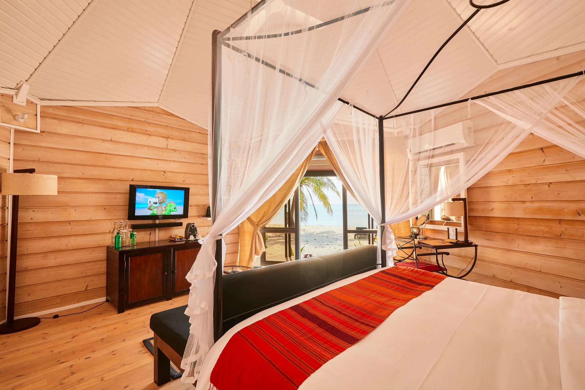 Interno della Jacuzzi Beach Villa con letto a baldacchino e vista mare al Kuredu Island Resort & Spa.