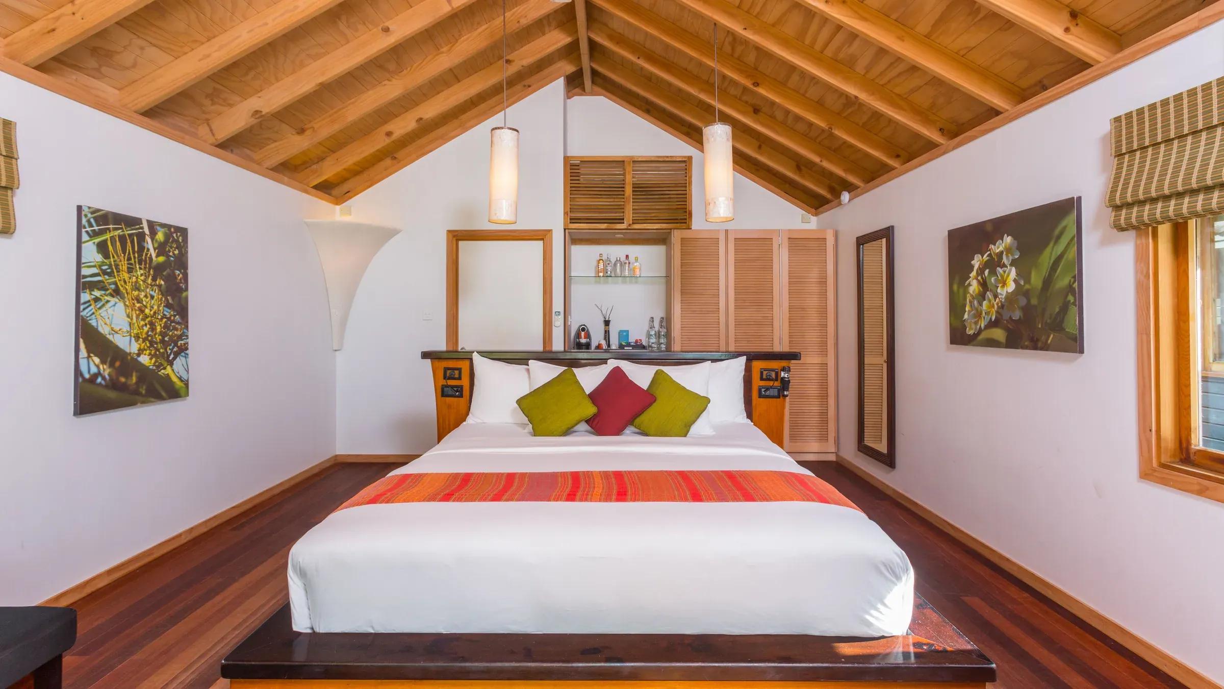 Letto matrimoniale con travi a vista nella O Beach Villa del Kuredu Island Resort & Spa.