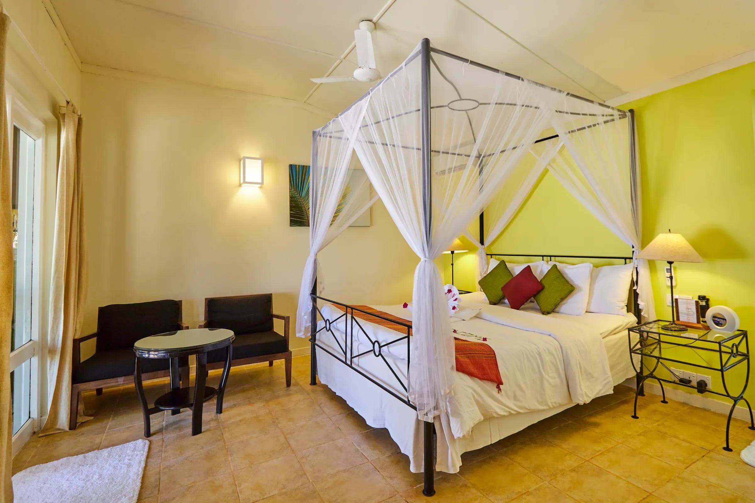 Interno della Premium Beach Bungalow con letto a baldacchino e area salotto al Kuredu Island Resort & Spa.