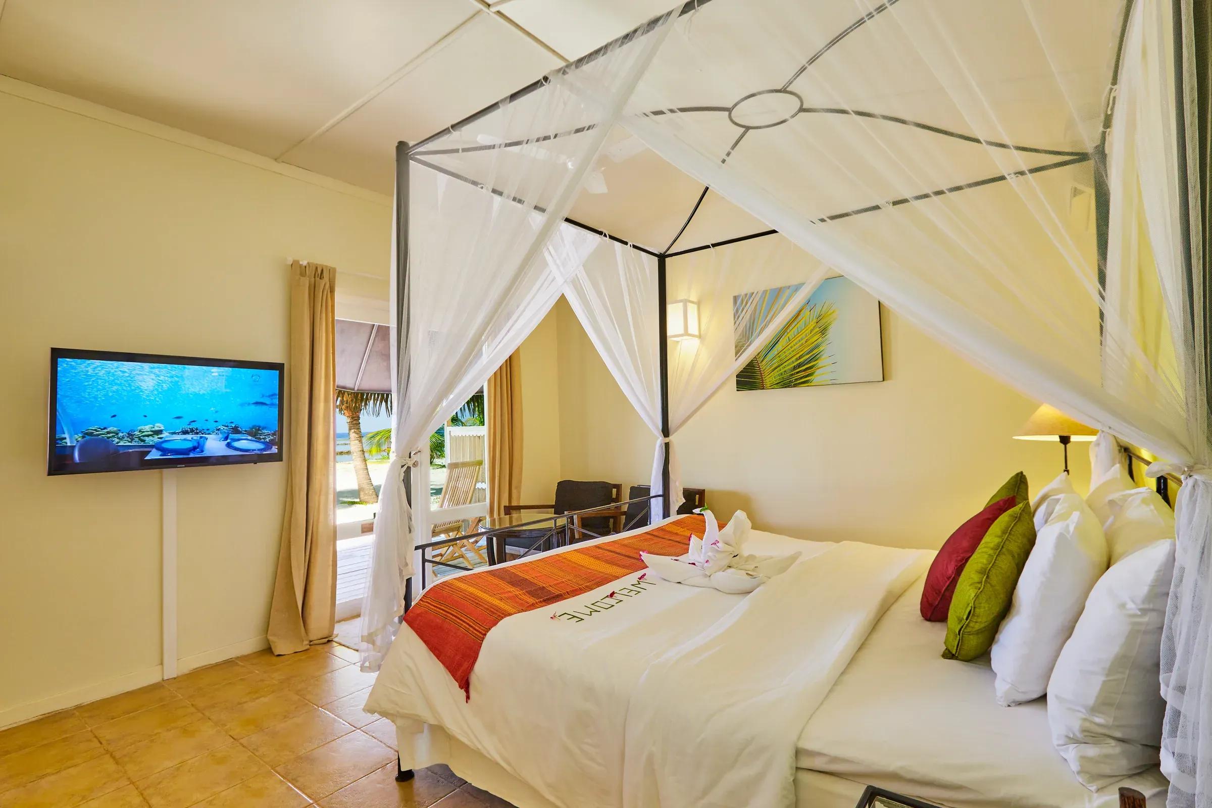 Interno della Premium Beach Bungalow con letto a baldacchino e terrazza vista mare al Kuredu Island Resort & Spa.